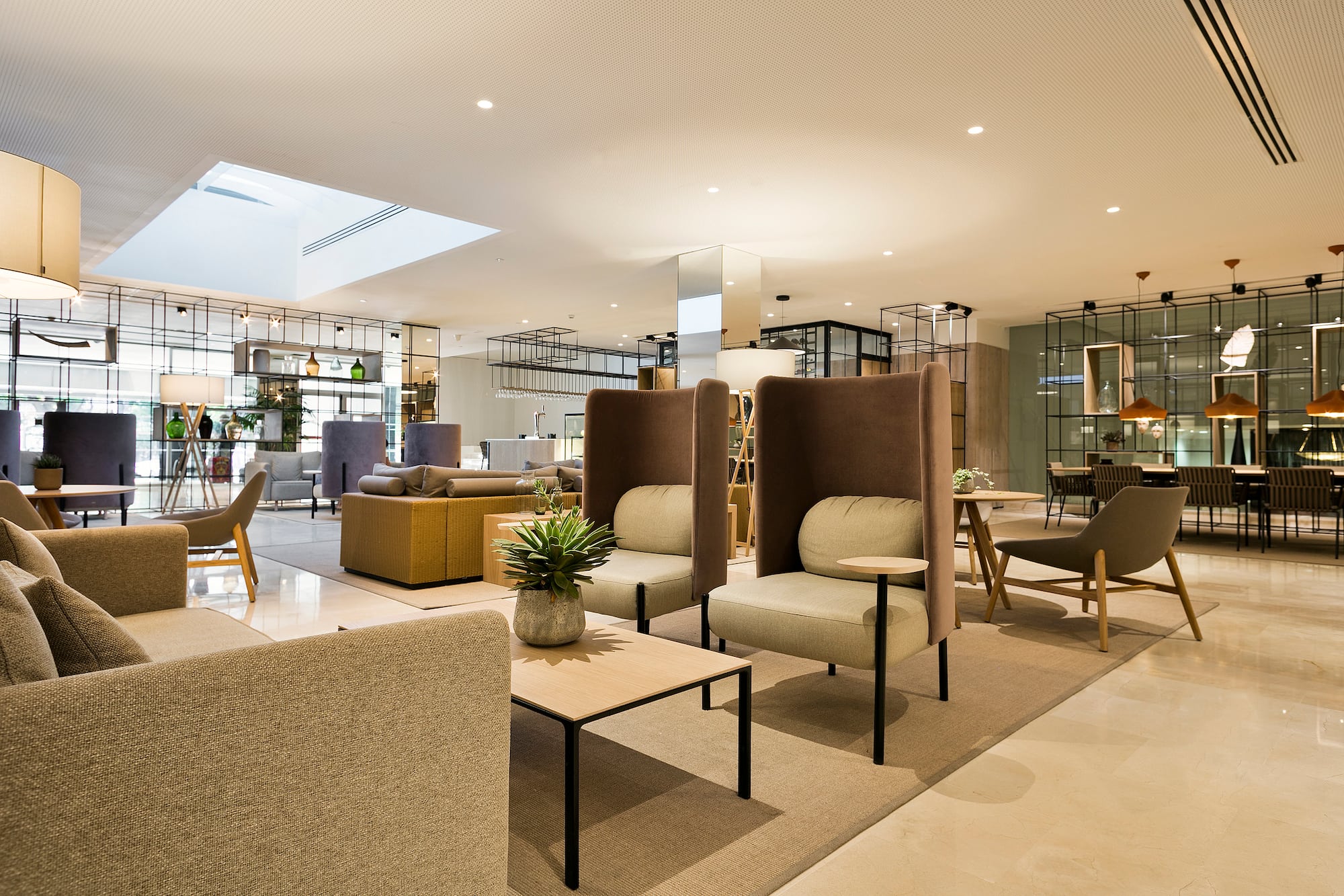Modern hotel lounge with various seating, coffee tables, and a bright, contemporary design.