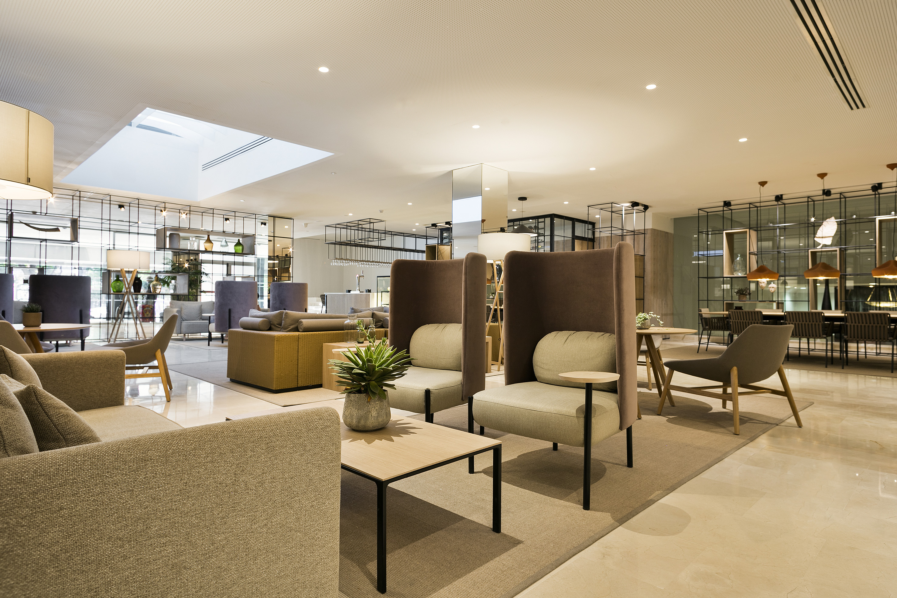 Modern hotel lounge with various seating, coffee tables, and a bright, contemporary design.
