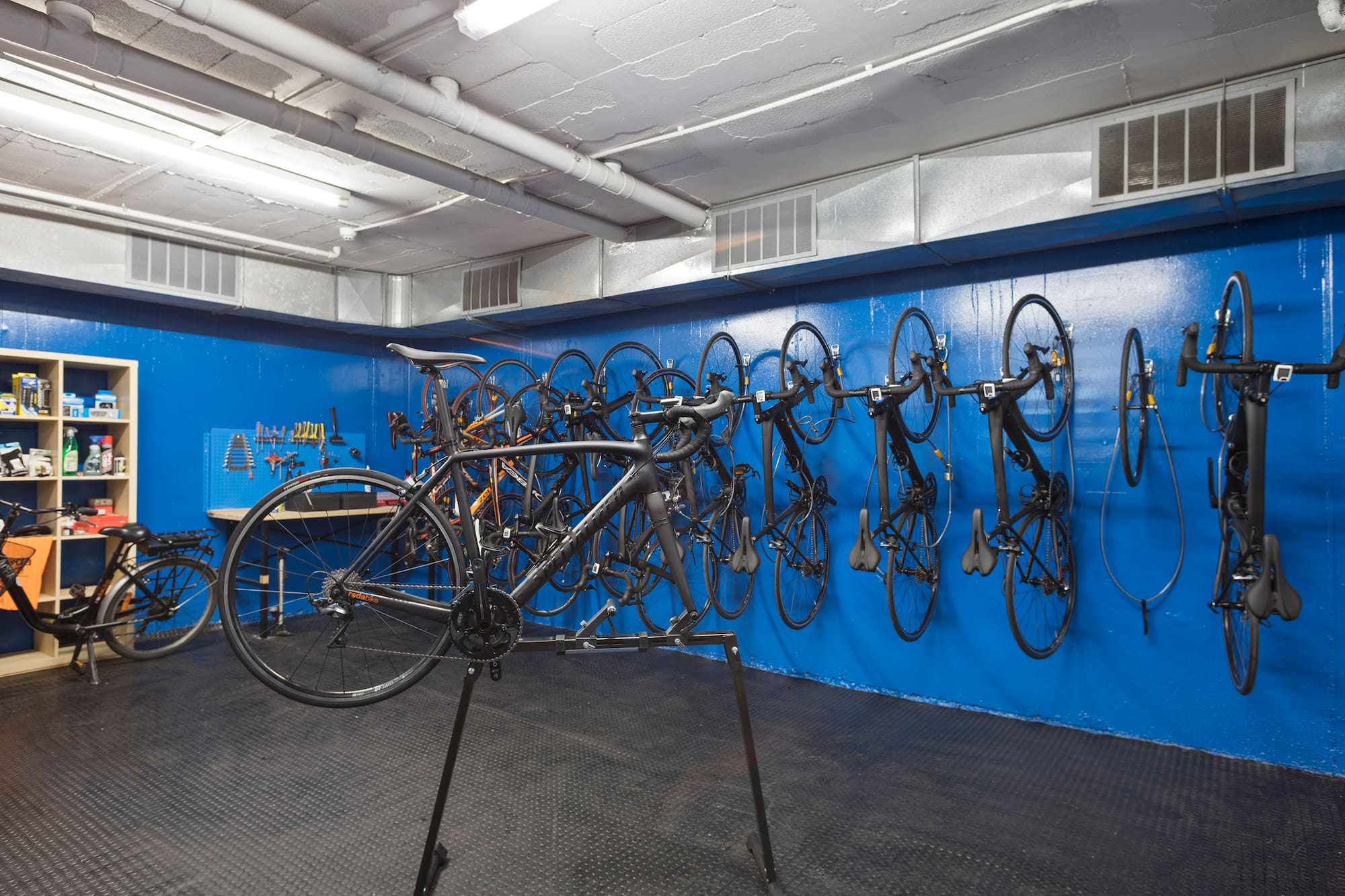 Bicycle storage and repair room with bikes, work stand, and tools.