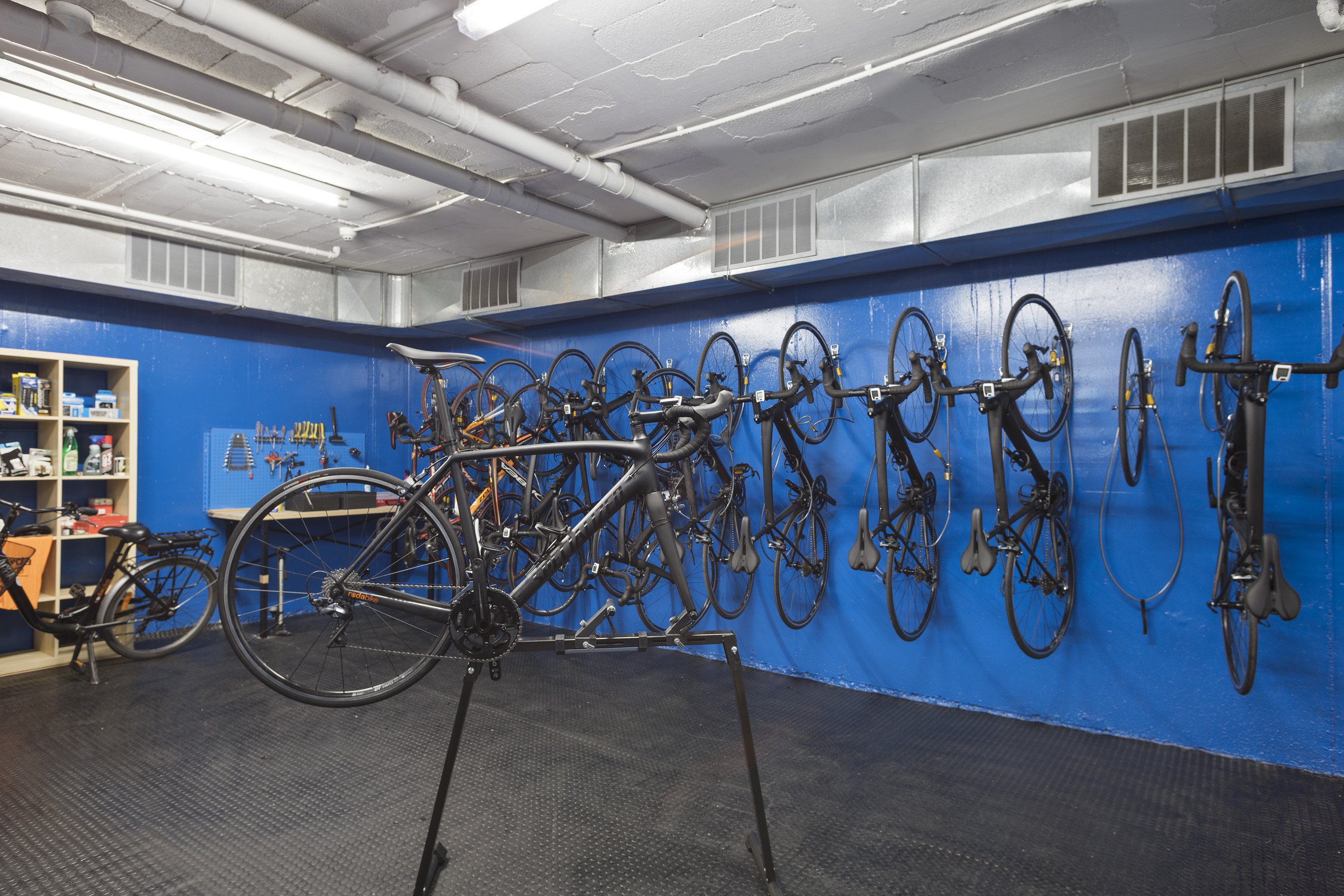 Bicycle storage and repair room with bikes, work stand, and tools.