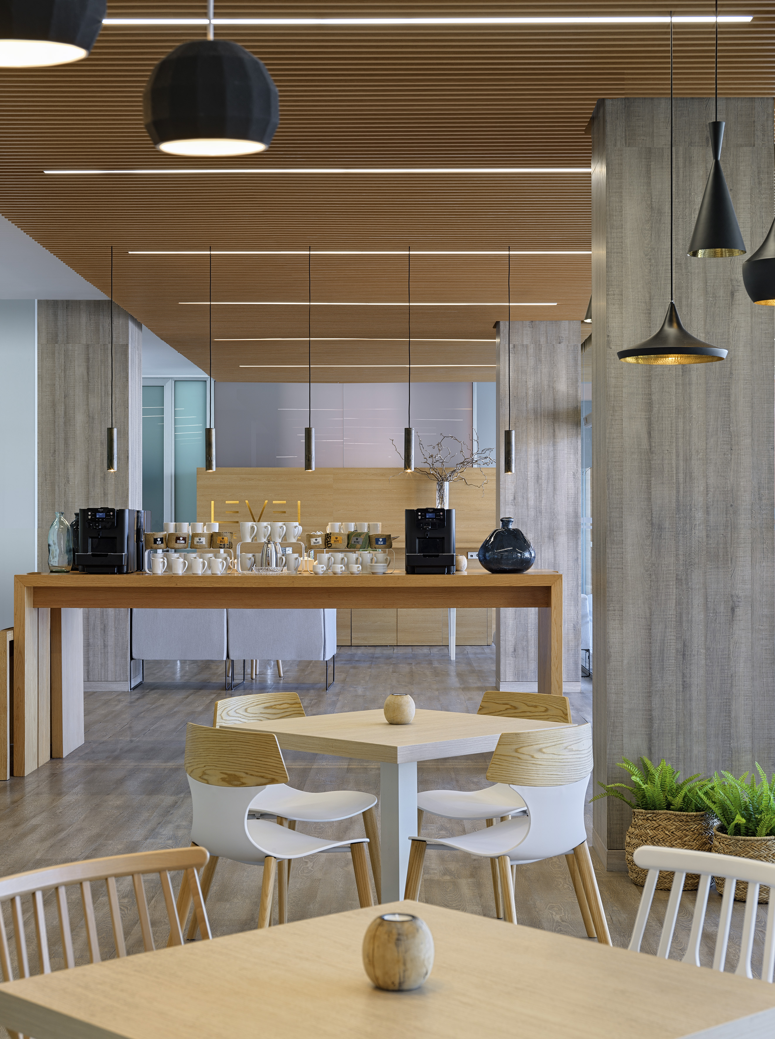 Modern office breakroom with coffee bar, wood ceiling, and stylish seating.