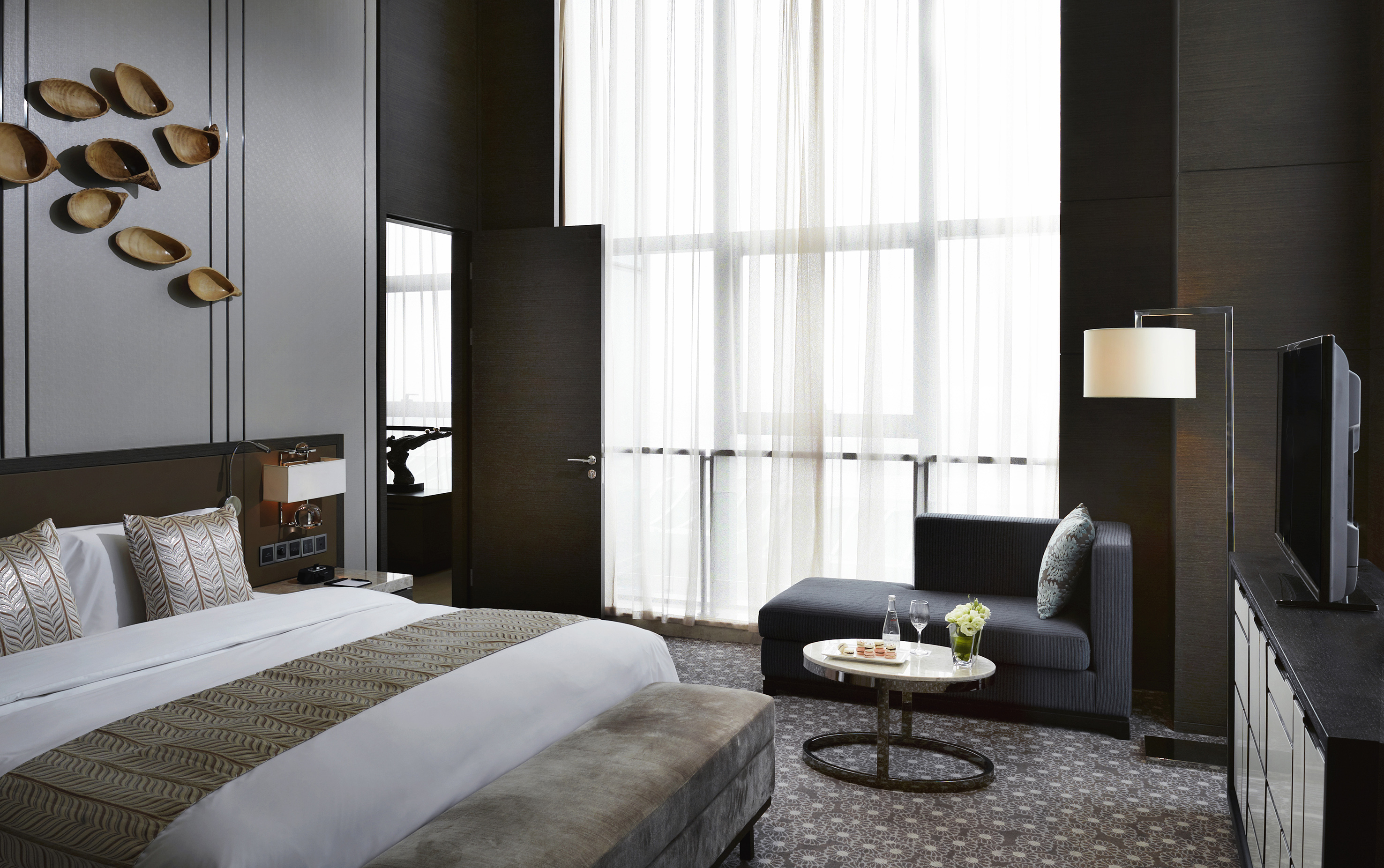 Luxury hotel suite with modern bedroom, chic decor, and bright windows.