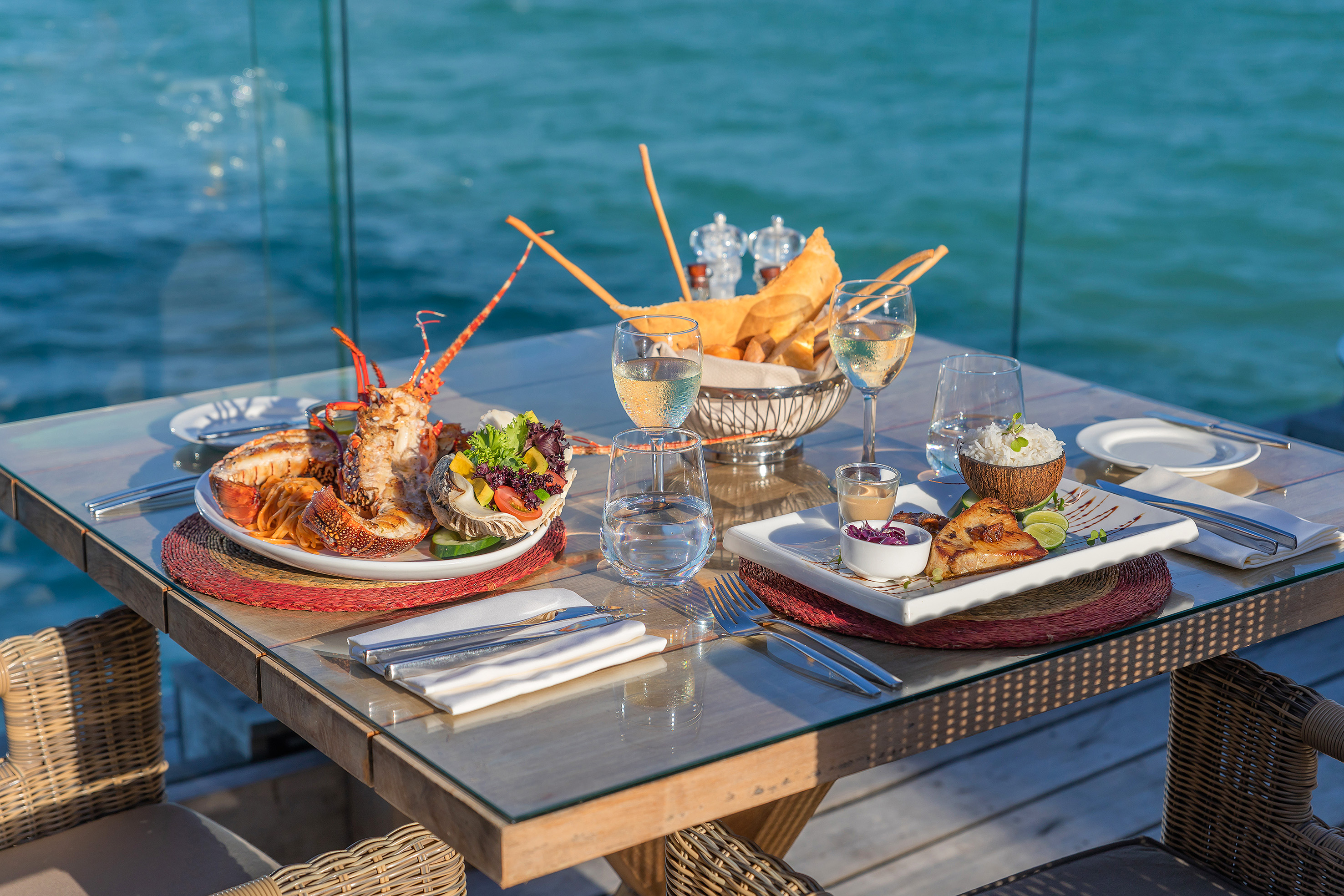 Luxurious oceanfront dining with grilled lobster, fish, and wine.