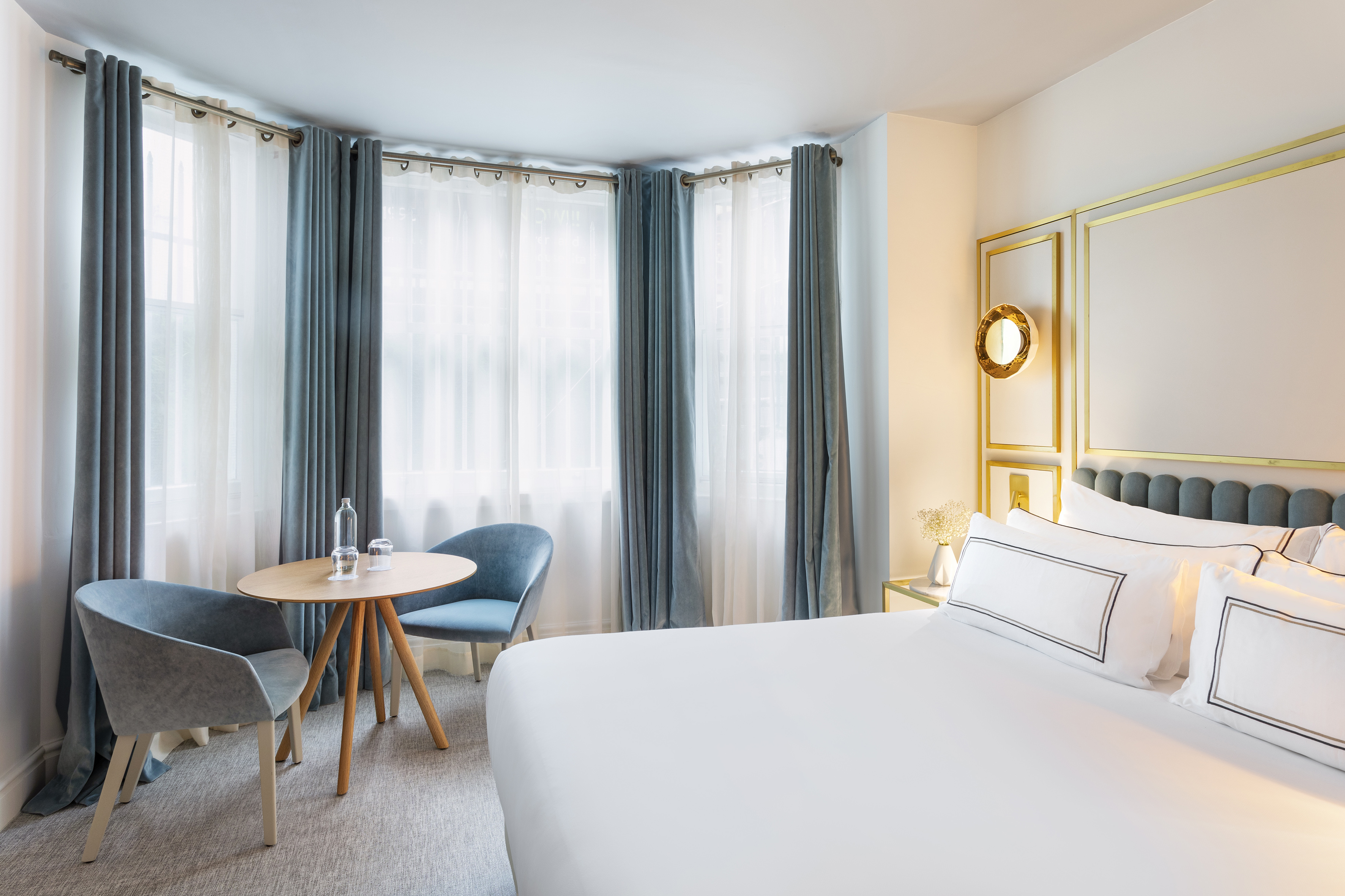 Luxury hotel bedroom with a large bed, blue curtains, and gold decor.