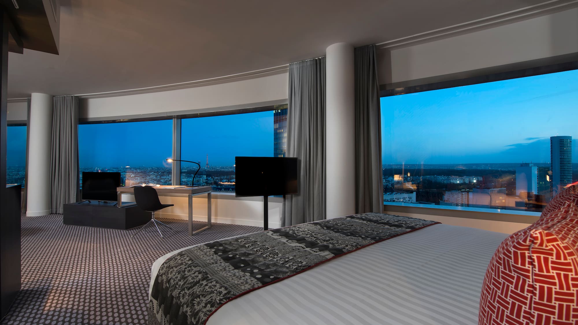 a room with a large bed and a desk and a large window