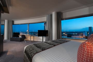 a room with a large bed and a desk and a large window