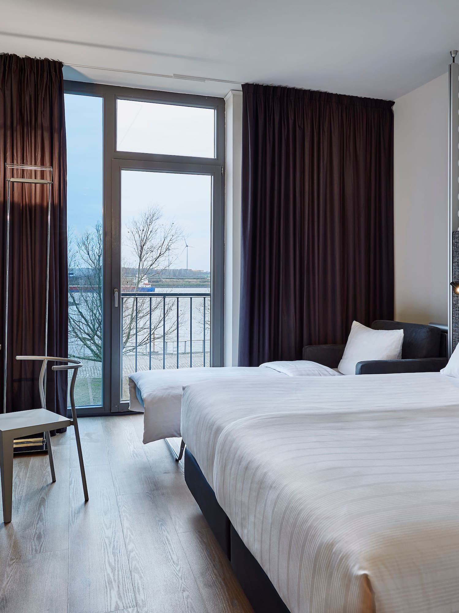 Modern hotel room with twin beds, river view, and contemporary design.