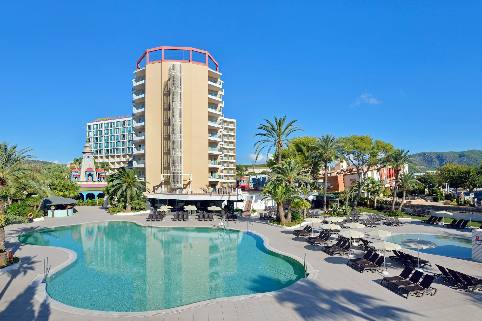 a pool with lounge chairs and a building in the background