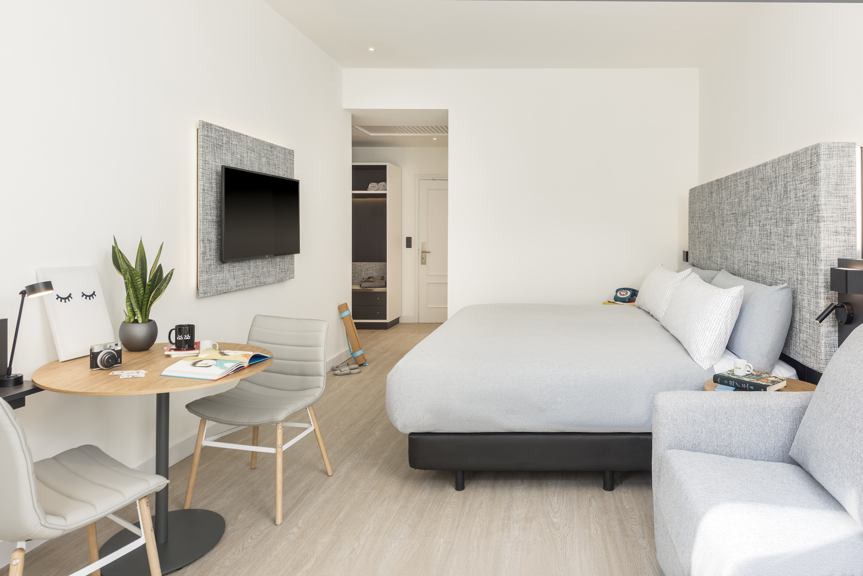 Bright modern hotel room with bed, desk, TV, and comfortable seating.