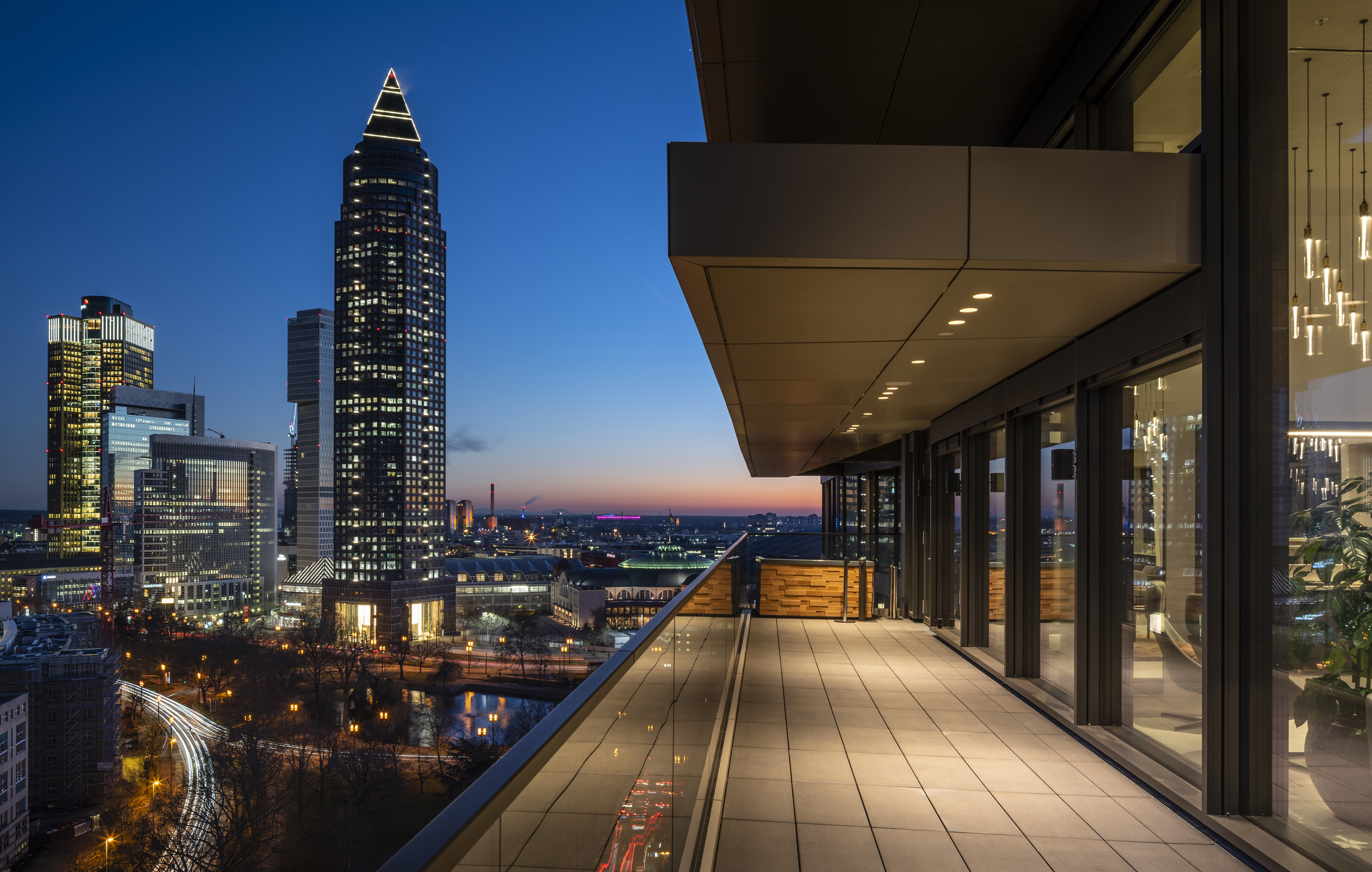 Balcony view of illuminated Frankfurt skyline at dusk, modern skyscrapers.