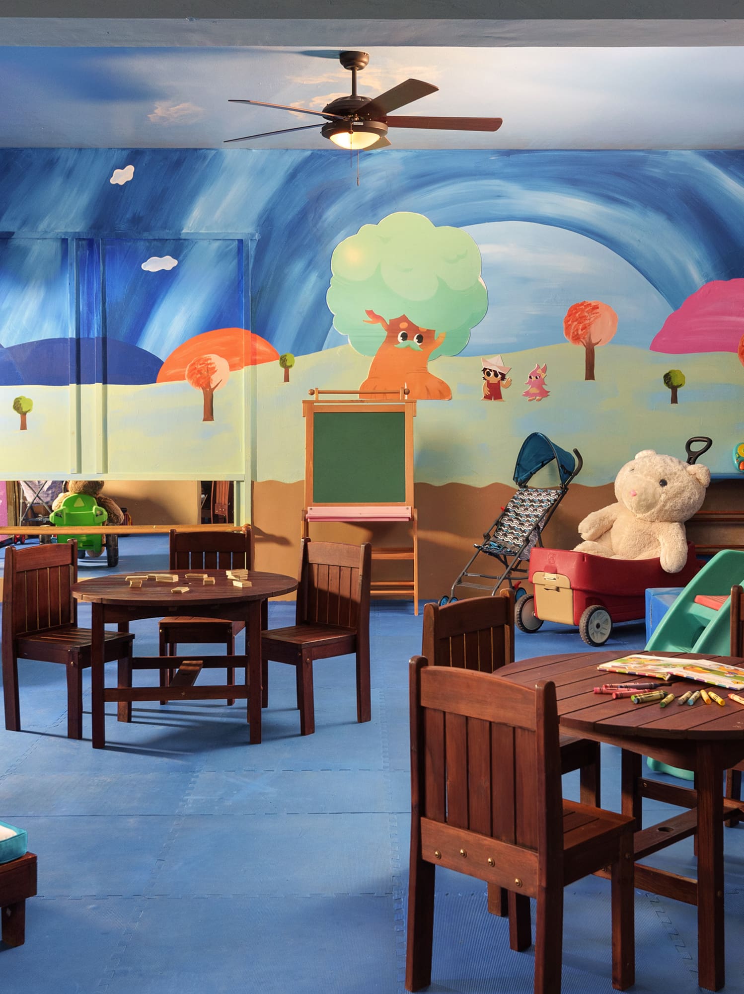 a room with a mural of a cartoon landscape and a table and chairs