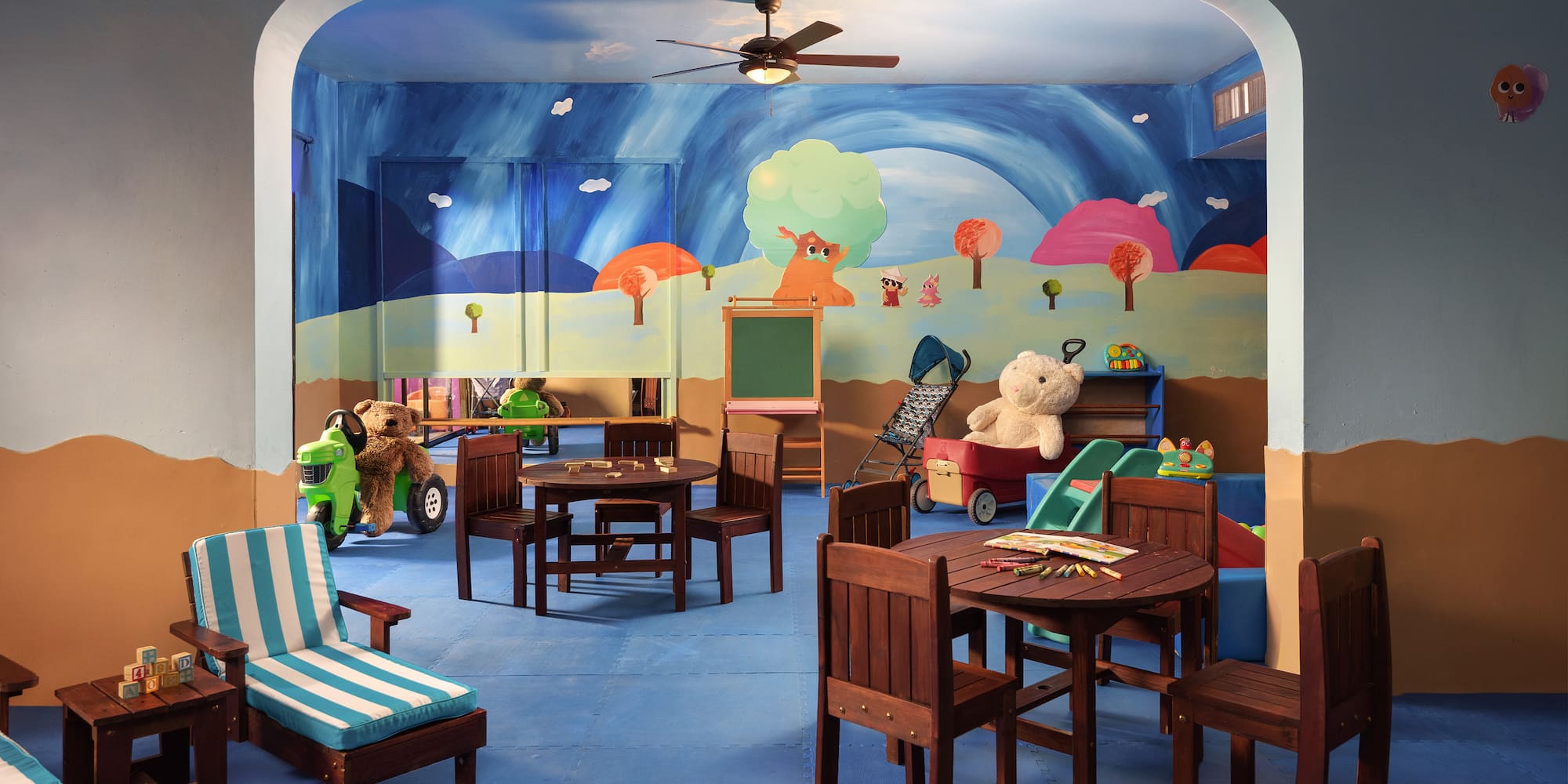 a room with a mural of a cartoon landscape and a table and chairs