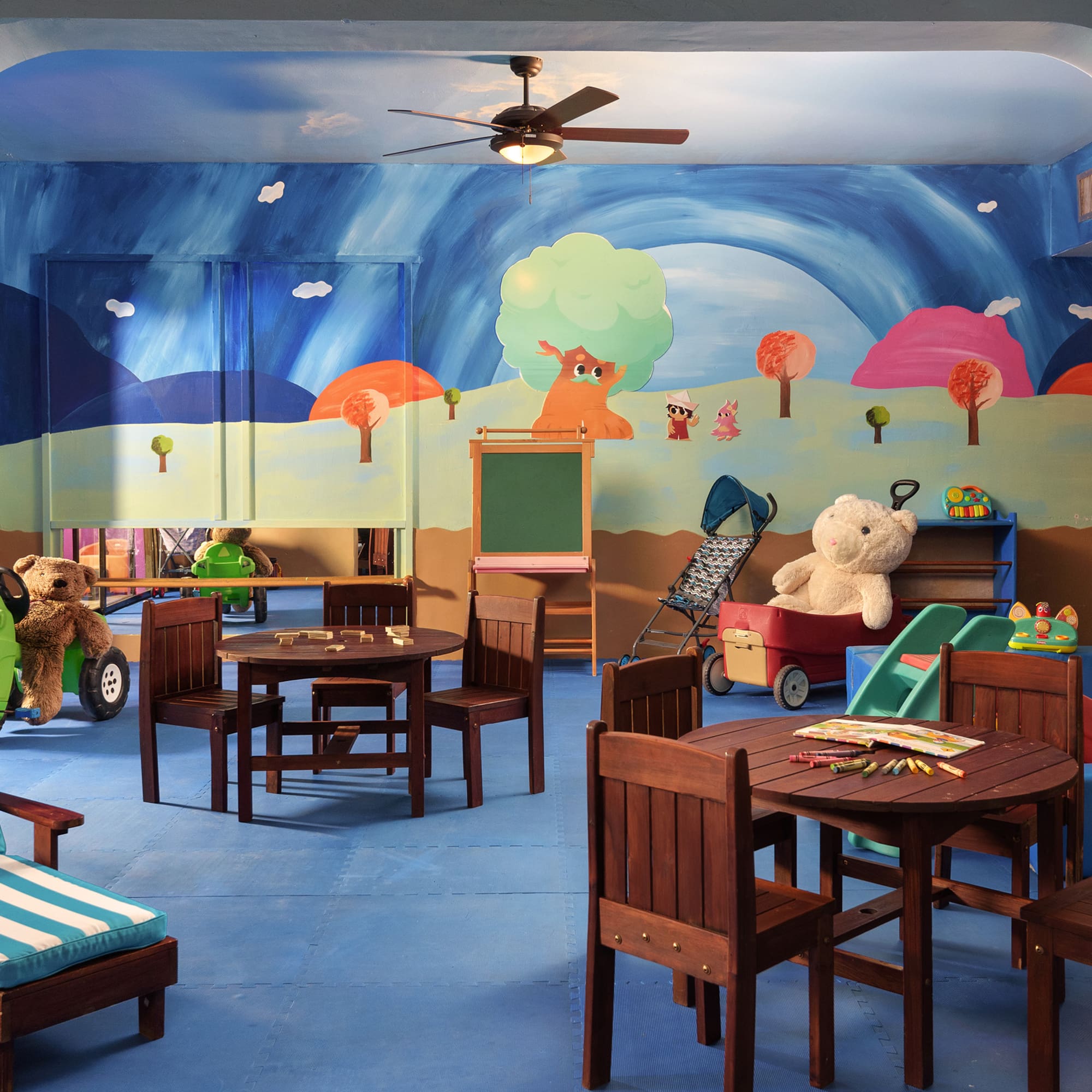 a room with a mural of a cartoon landscape and a table and chairs