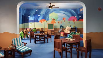 a room with a mural of a cartoon landscape and a table and chairs