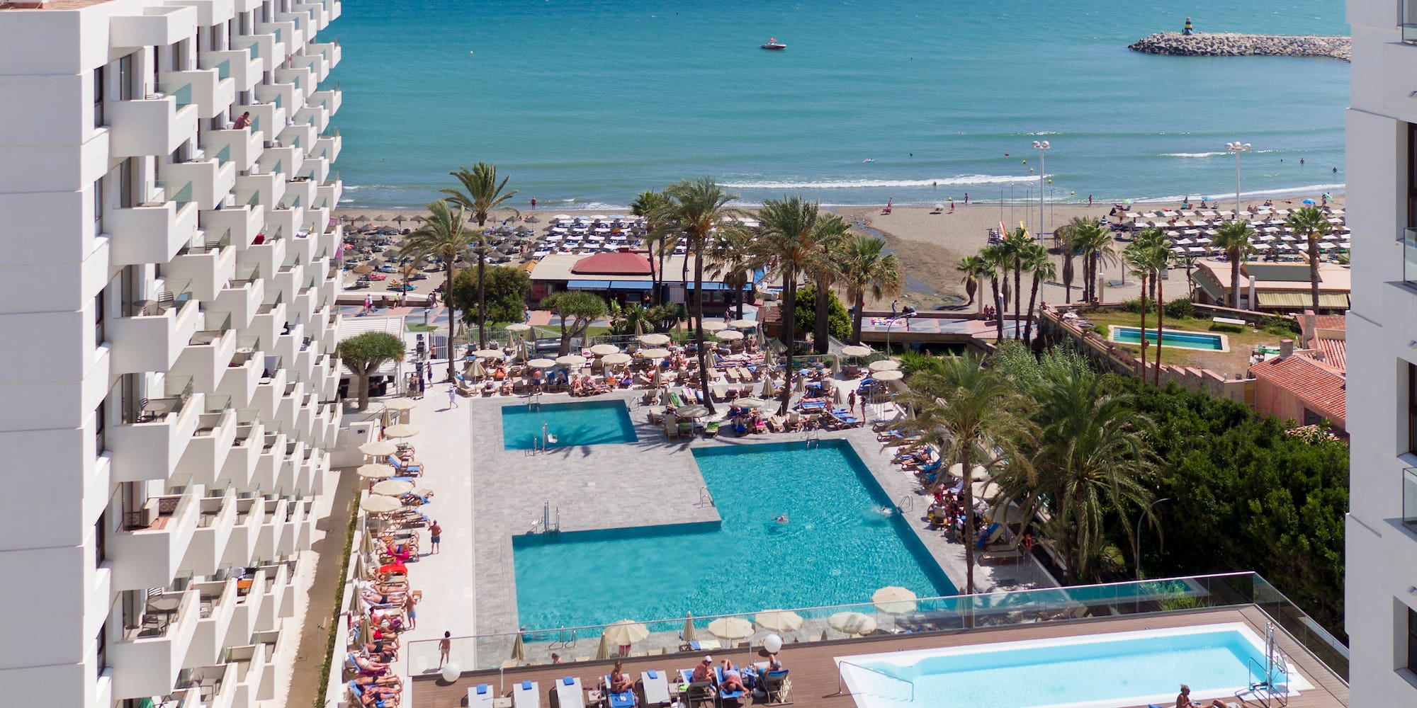 a pool and a building with a beach and water in the background