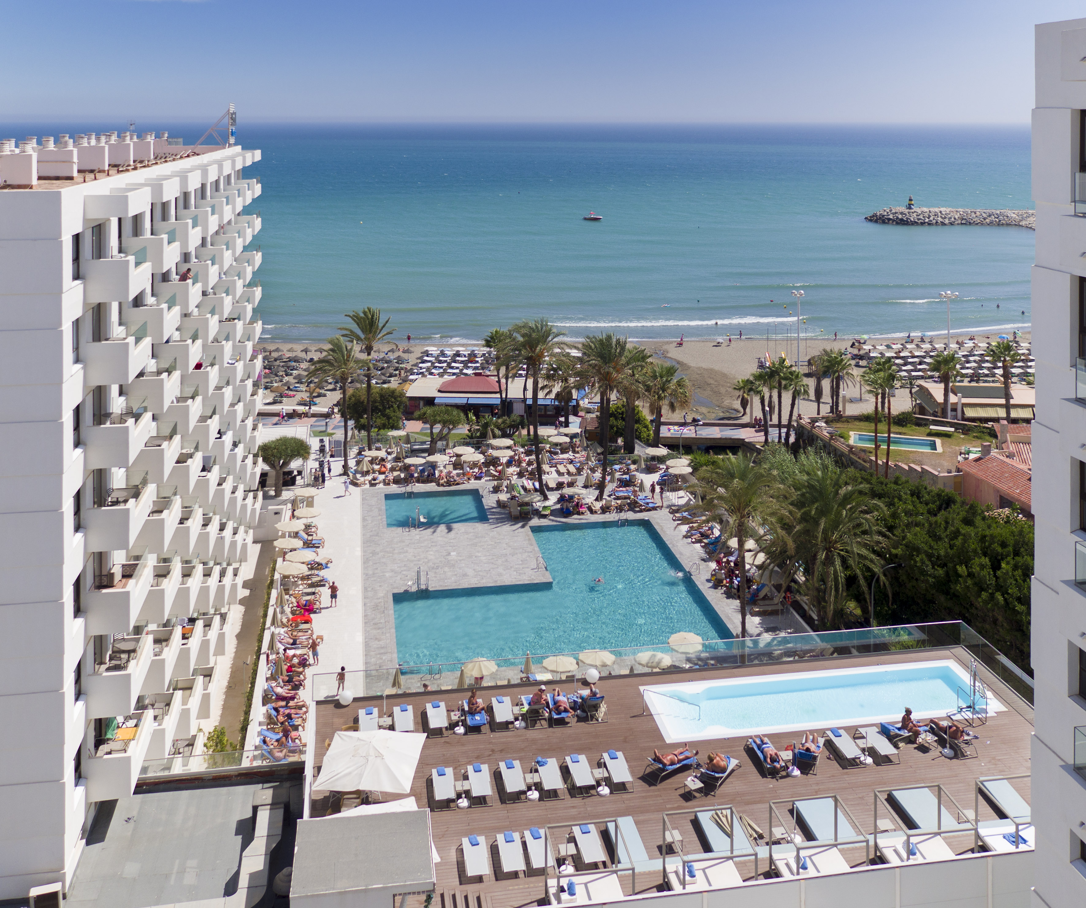 a pool and a building with a beach and water in the background