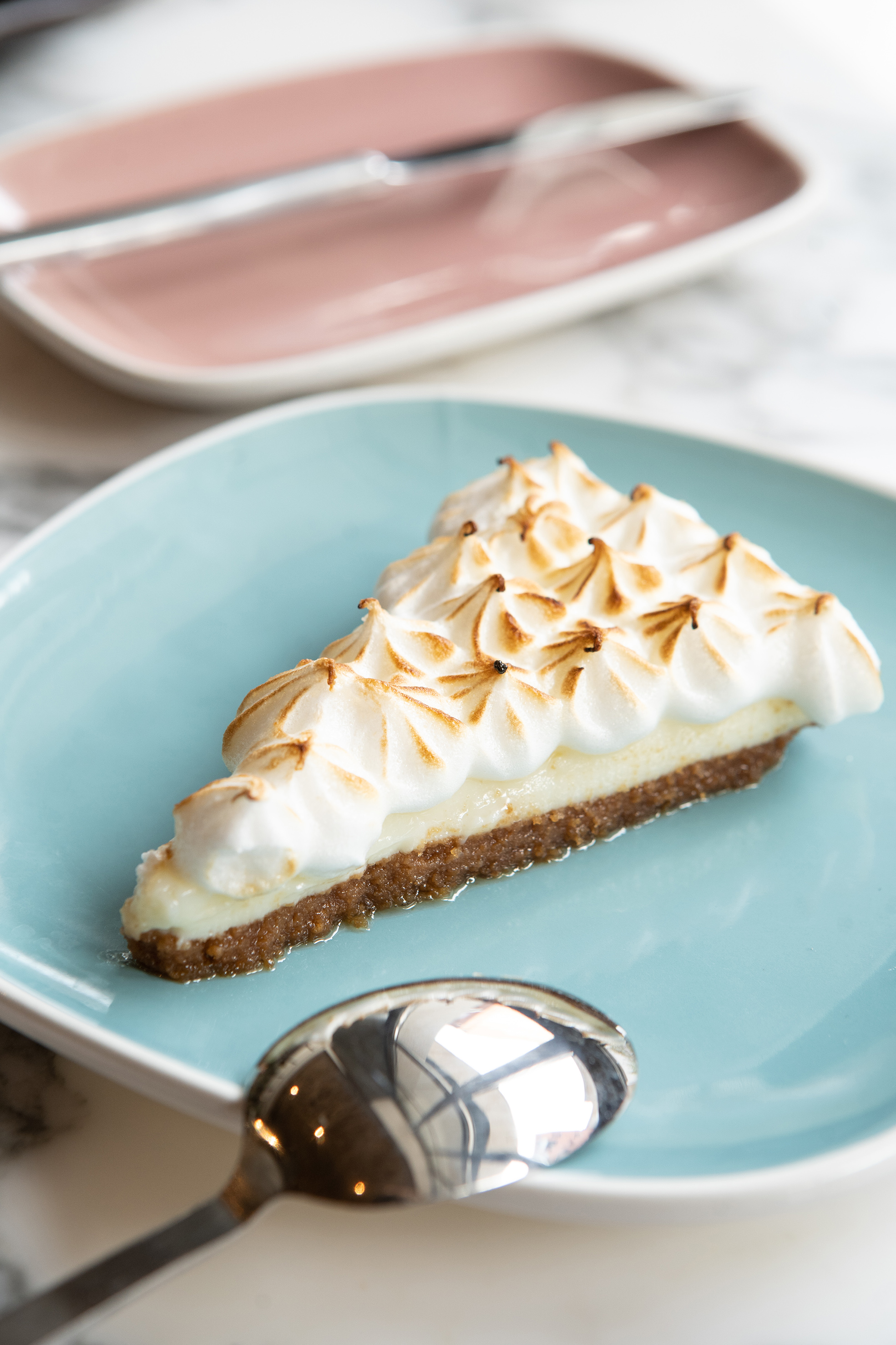 Dessert slice: Meringue pie with toasted peaks on a blue plate.