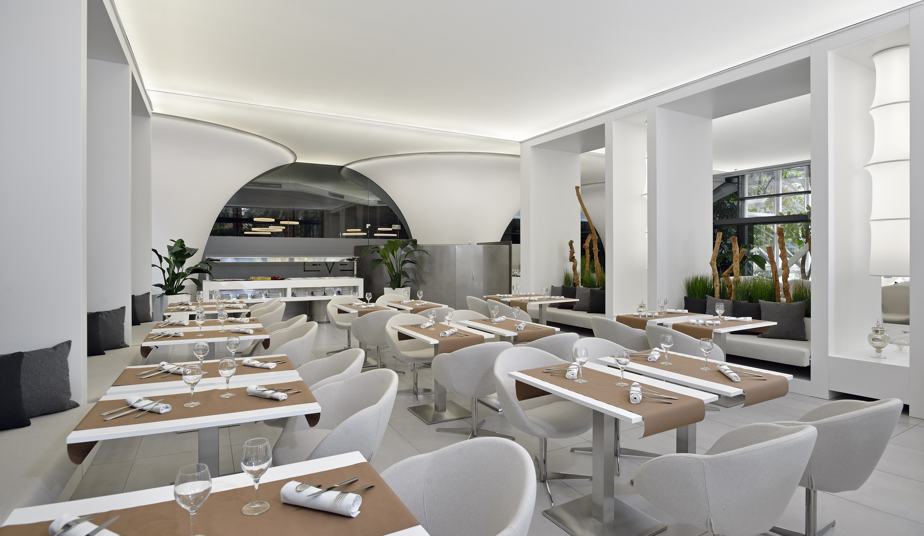 Modern hotel dining room with white decor, set tables, and buffet area.