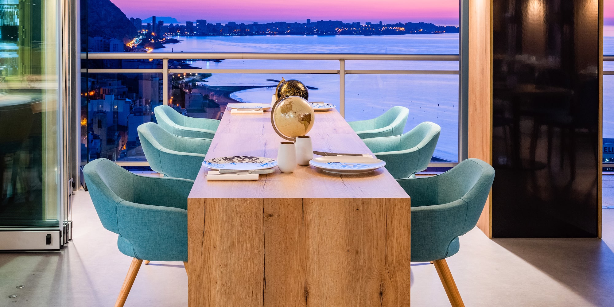a table with chairs and a view of the city from the window