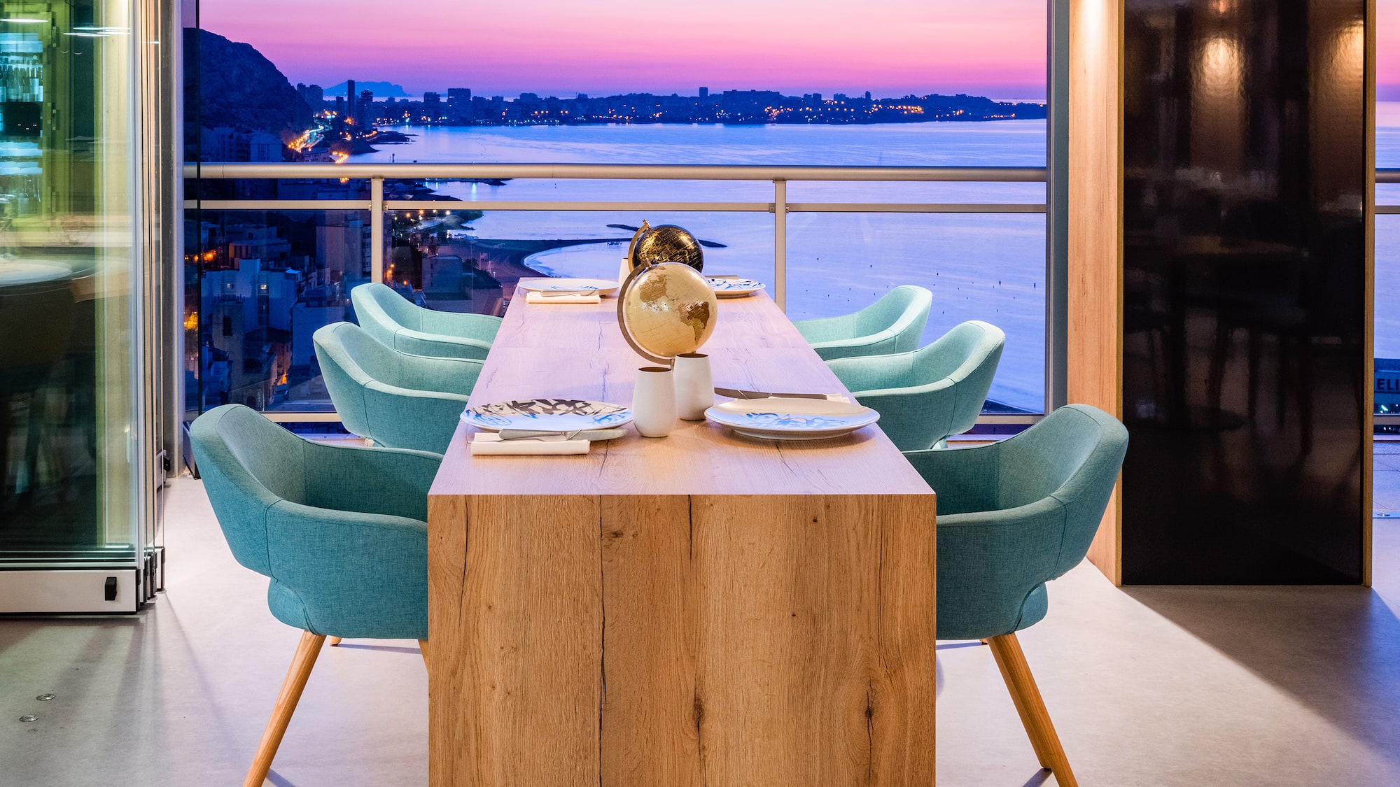 a table with chairs and a view of the city from the window