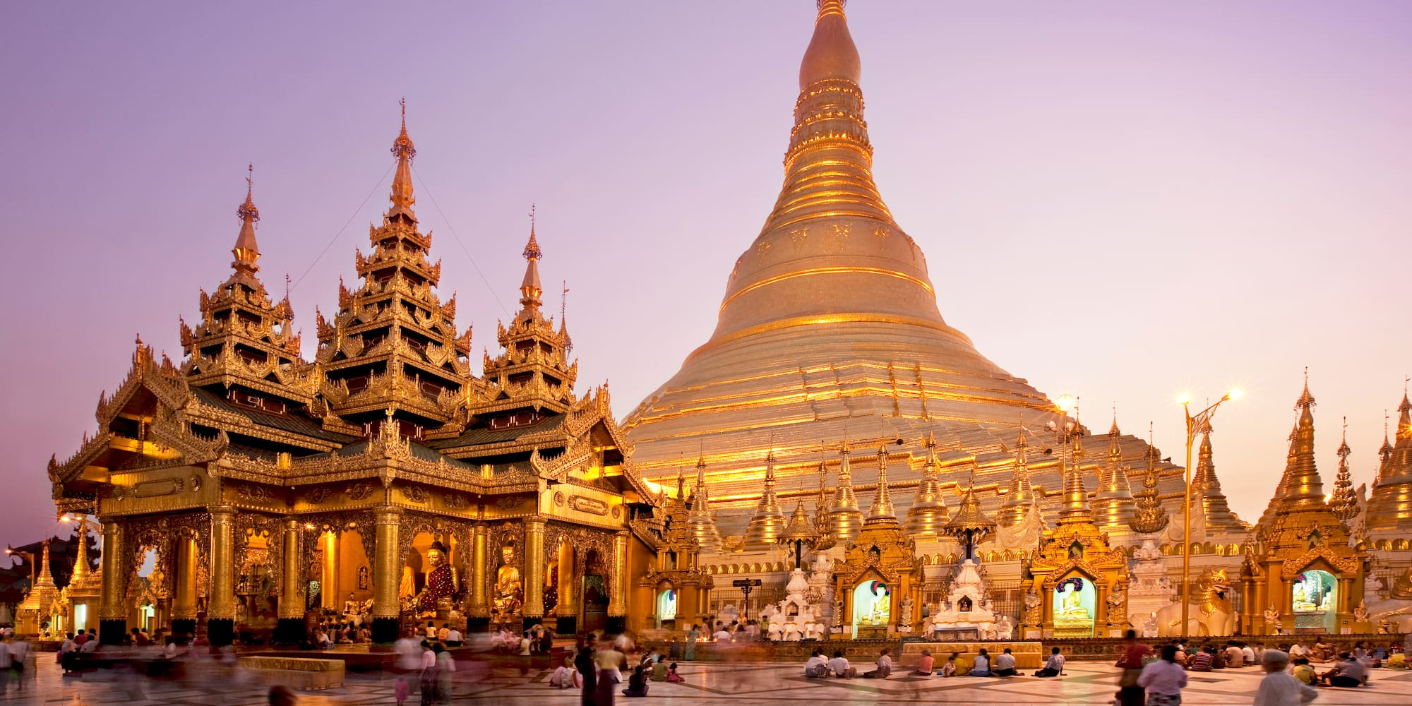 a large gold building with a pointed top with Shwedagon Pagoda in the background