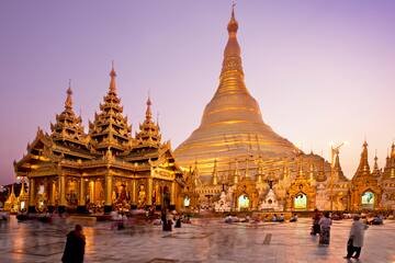 a large gold building with a pointed top with Shwedagon Pagoda in the background