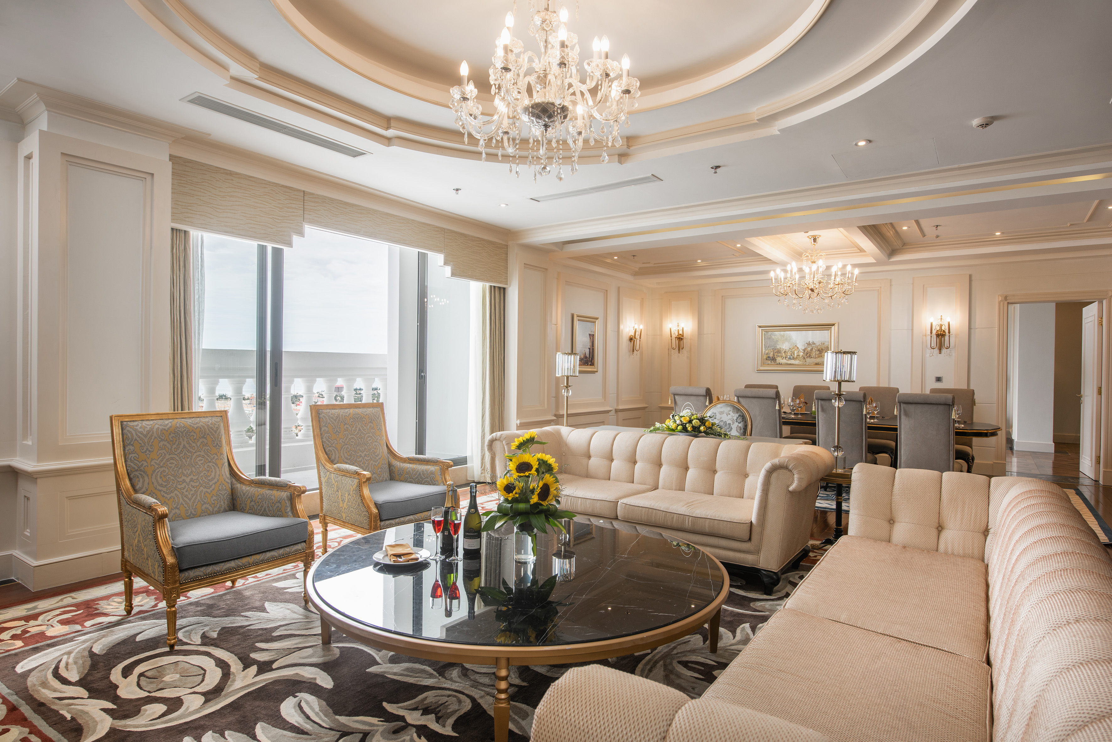 Luxury hotel suite living room with elegant decor, sofas, and dining area.