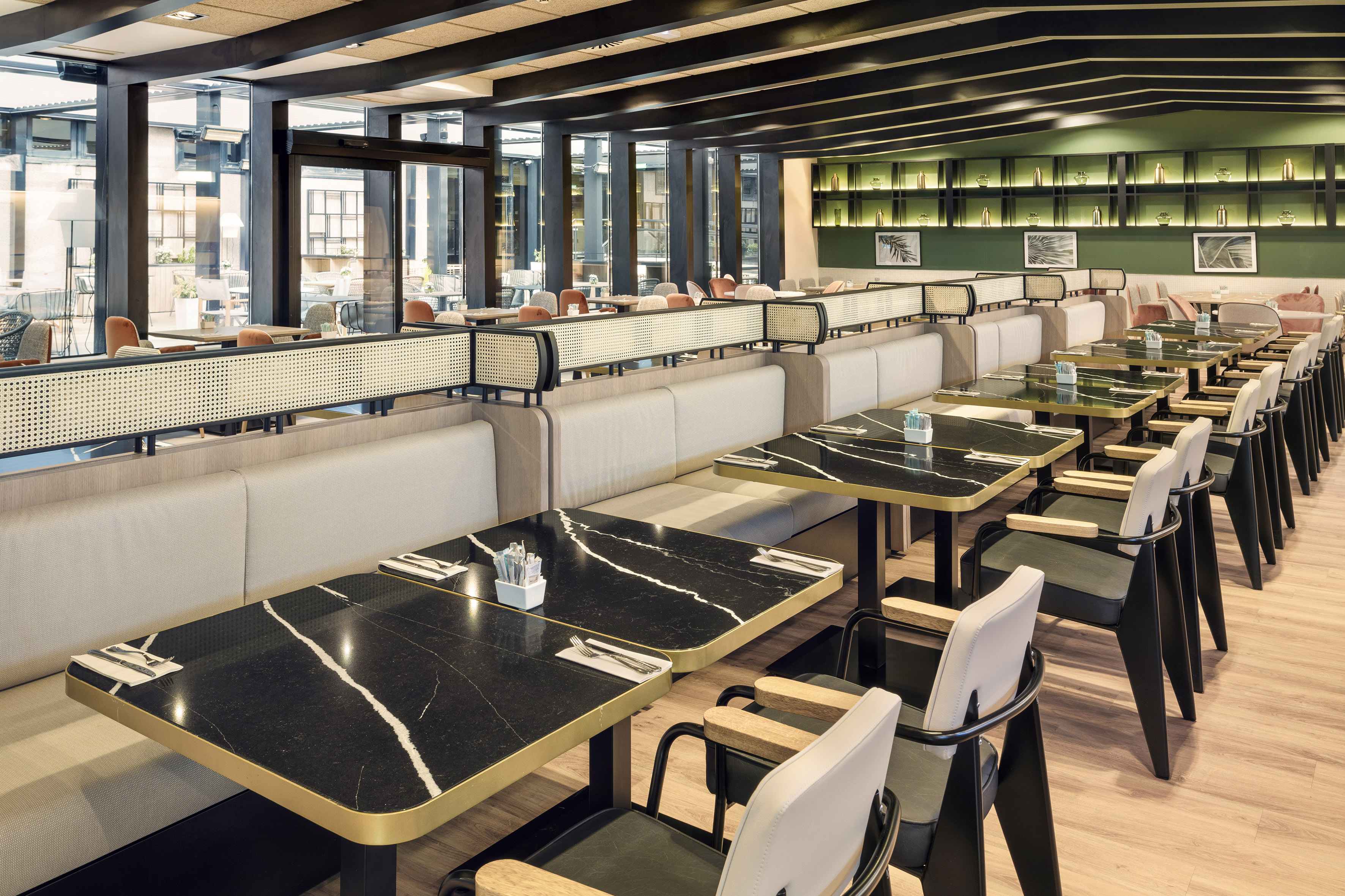 Modern restaurant with black marble tables, cream booths, and green wall decor.