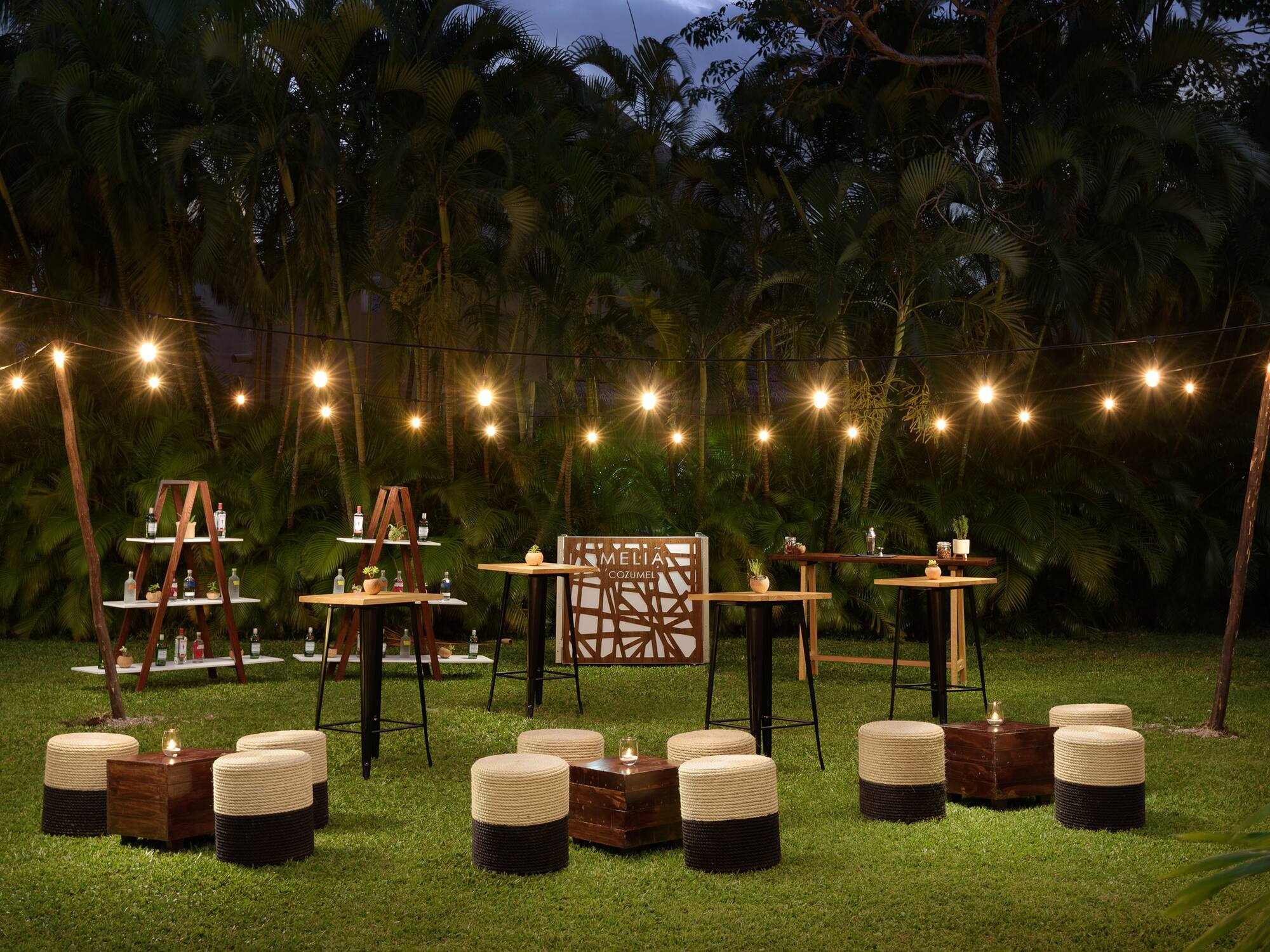 a group of tables and chairs in a grass area with lights