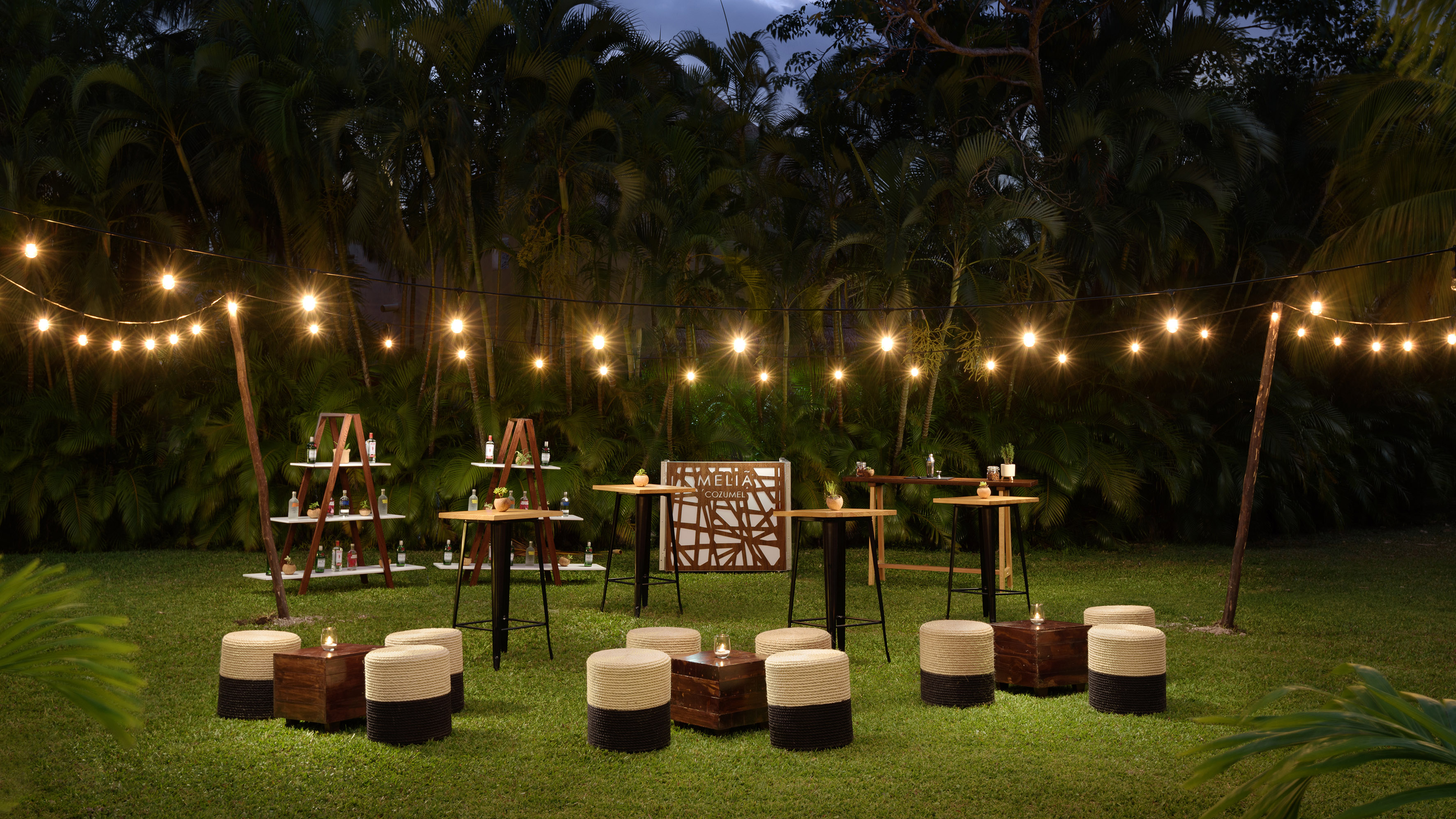 a group of tables and chairs in a grass area with lights