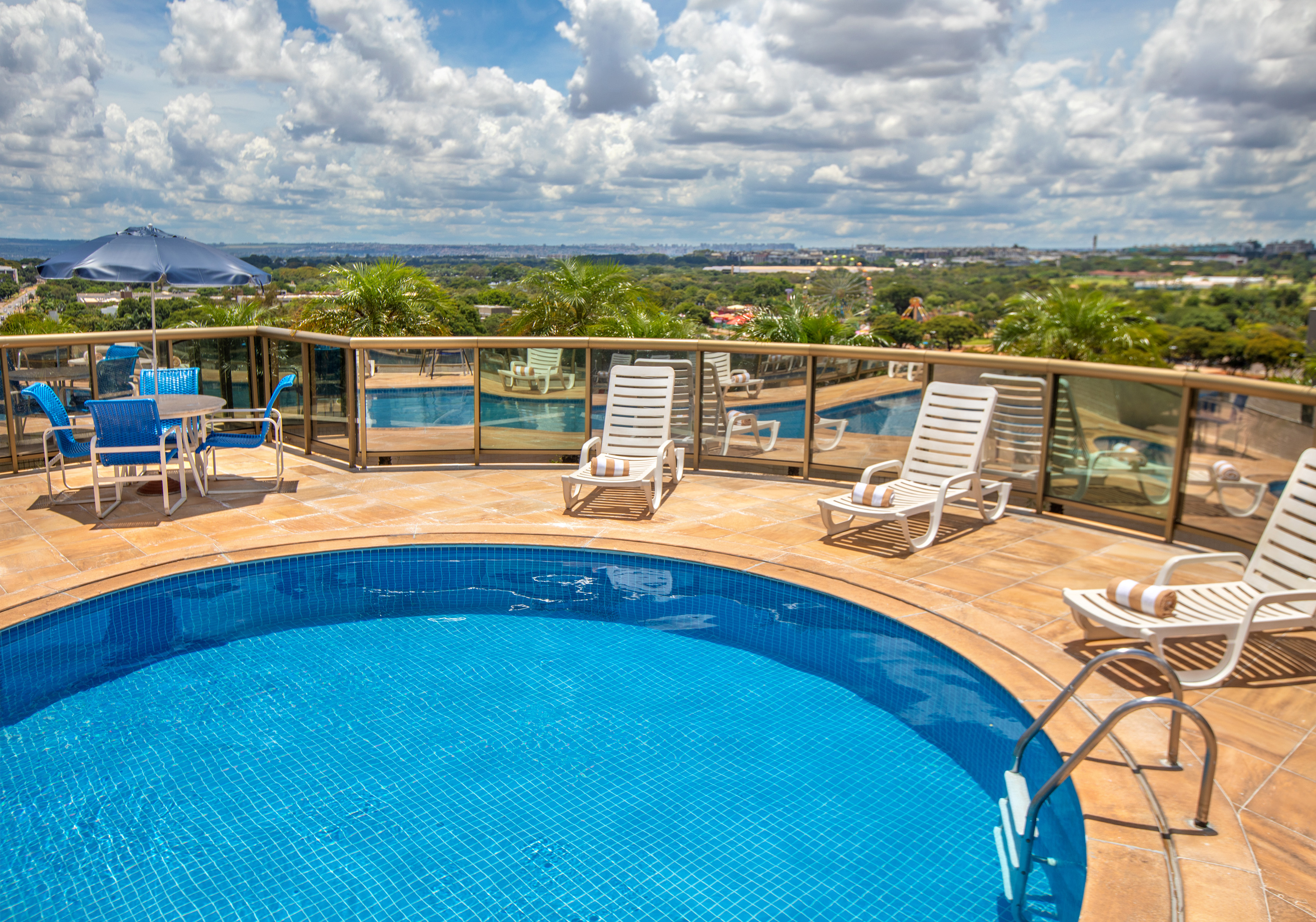 Hotel rooftop pool, lounge chairs, and panoramic city view.