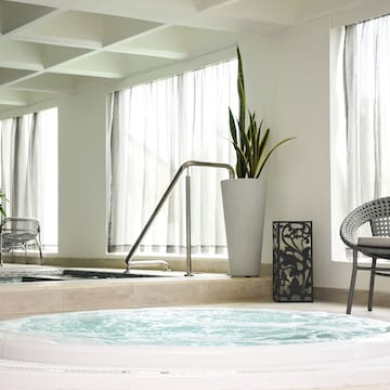 a hot tub in a room with windows and chairs