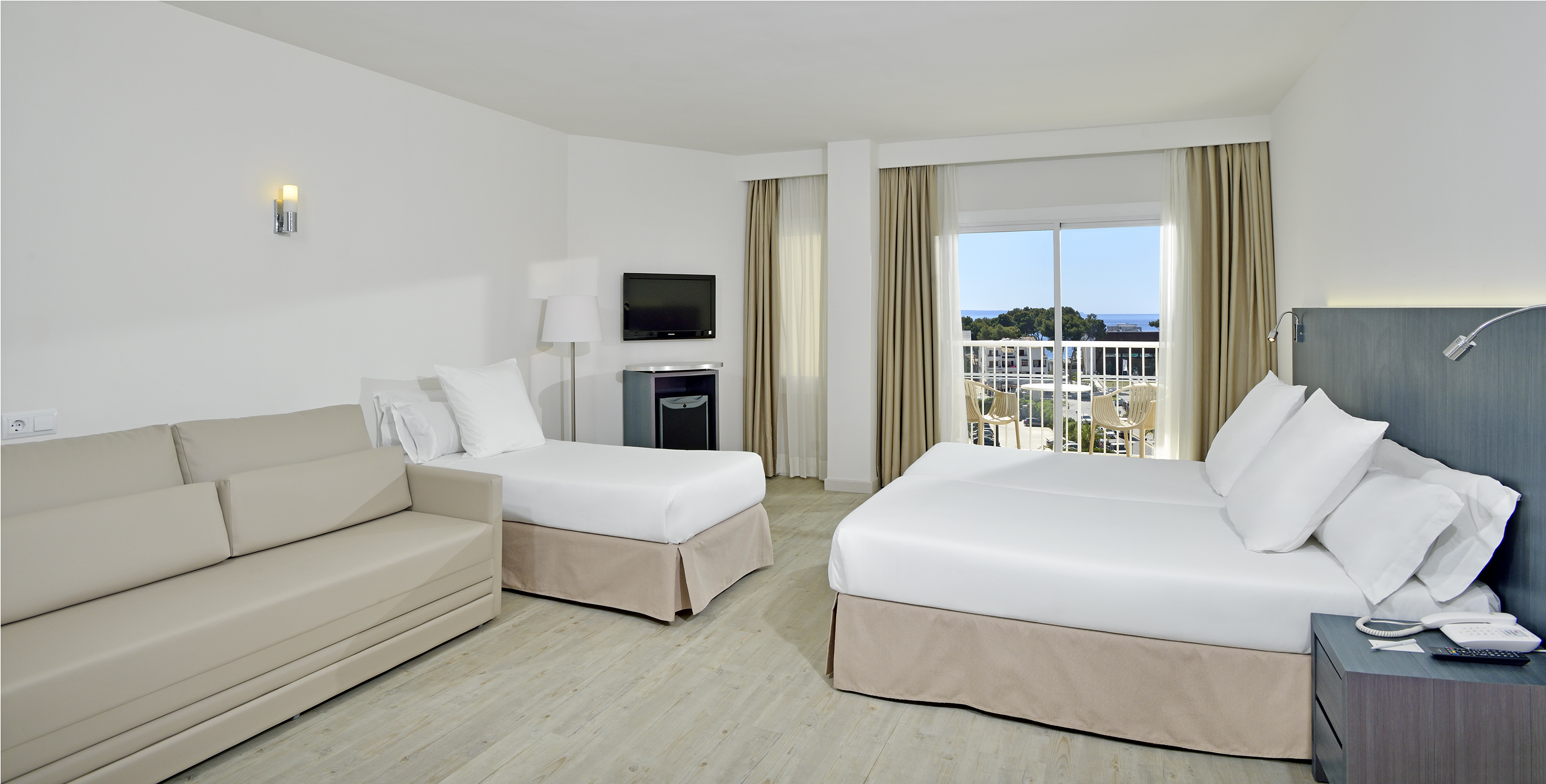 Hotel family room with twin beds, sofa bed, balcony, and sea view.