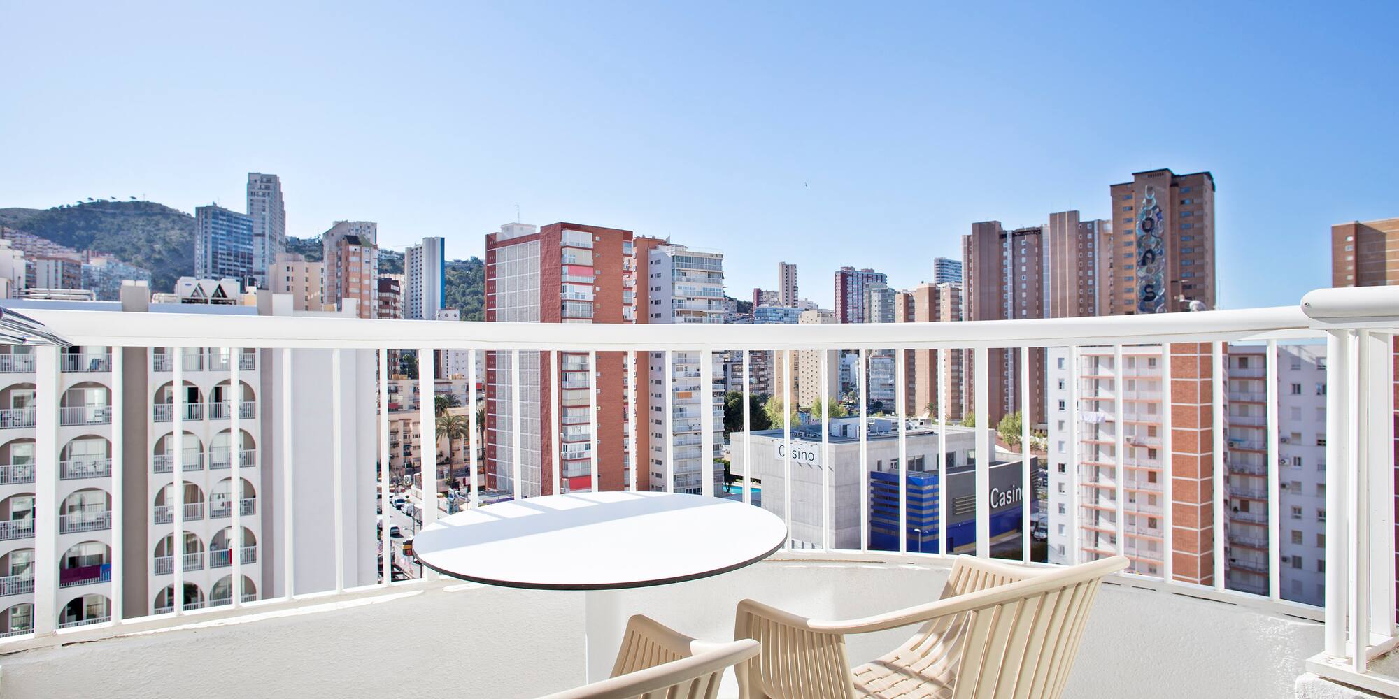 a table and chairs on a balcony with a city in the background