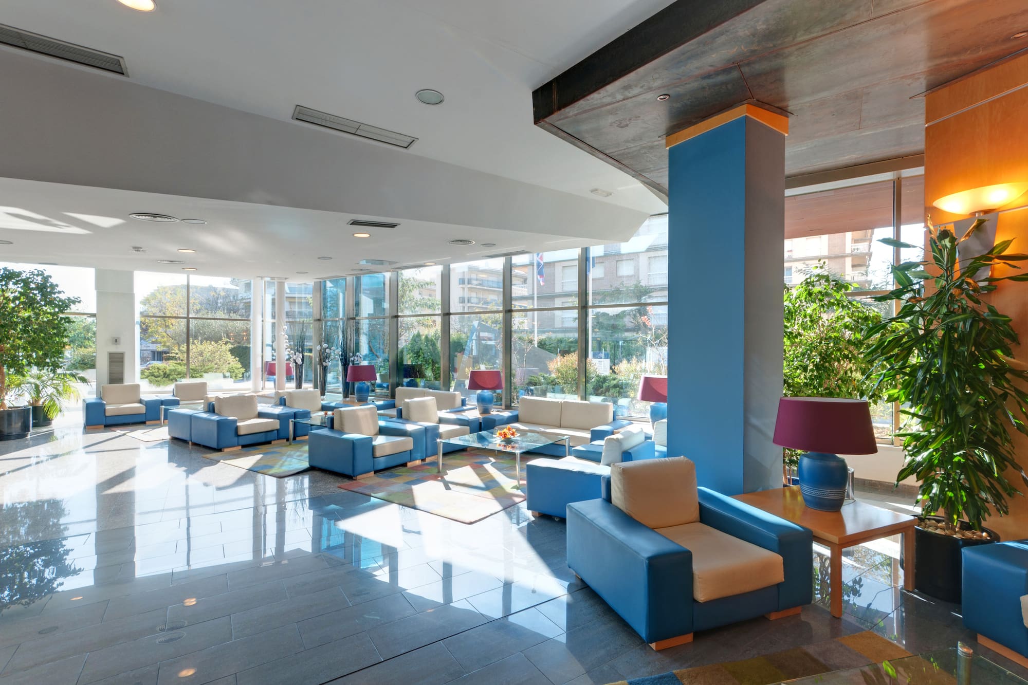 Modern hotel lobby with blue and beige seating, large windows, natural light.