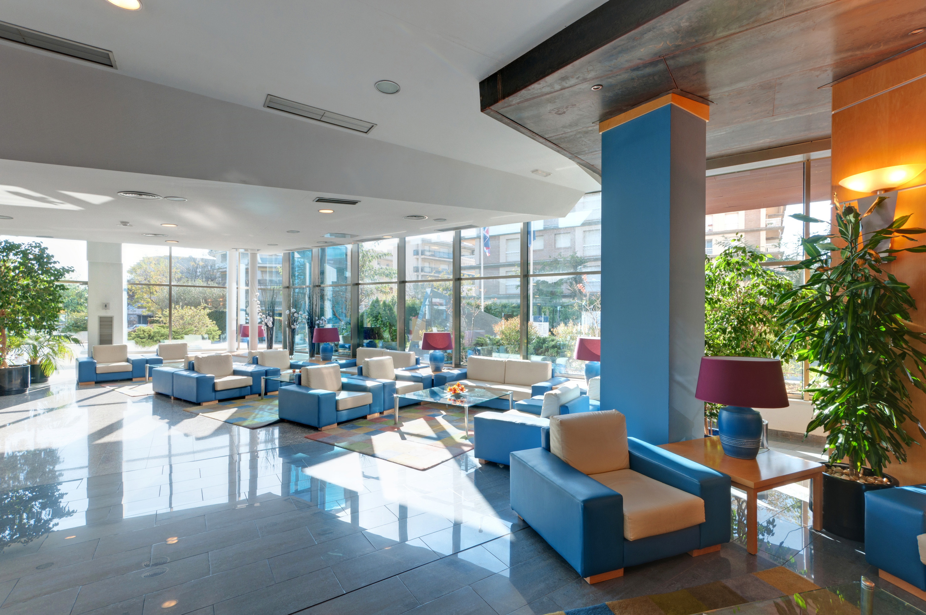 Modern hotel lobby with blue and beige seating, large windows, natural light.
