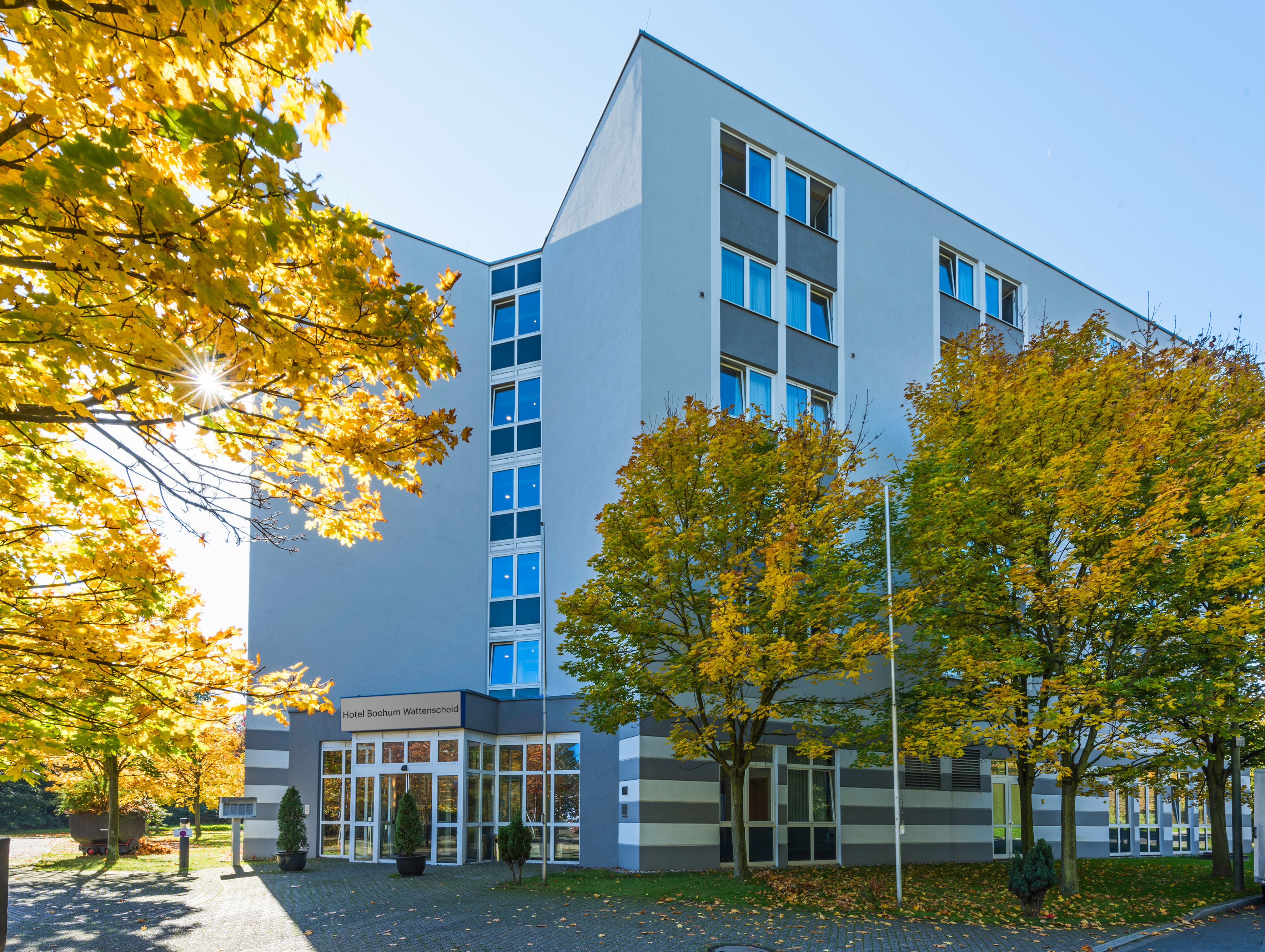 Hotel Bochum Wattenscheid in autumn, modern building with golden leaves.