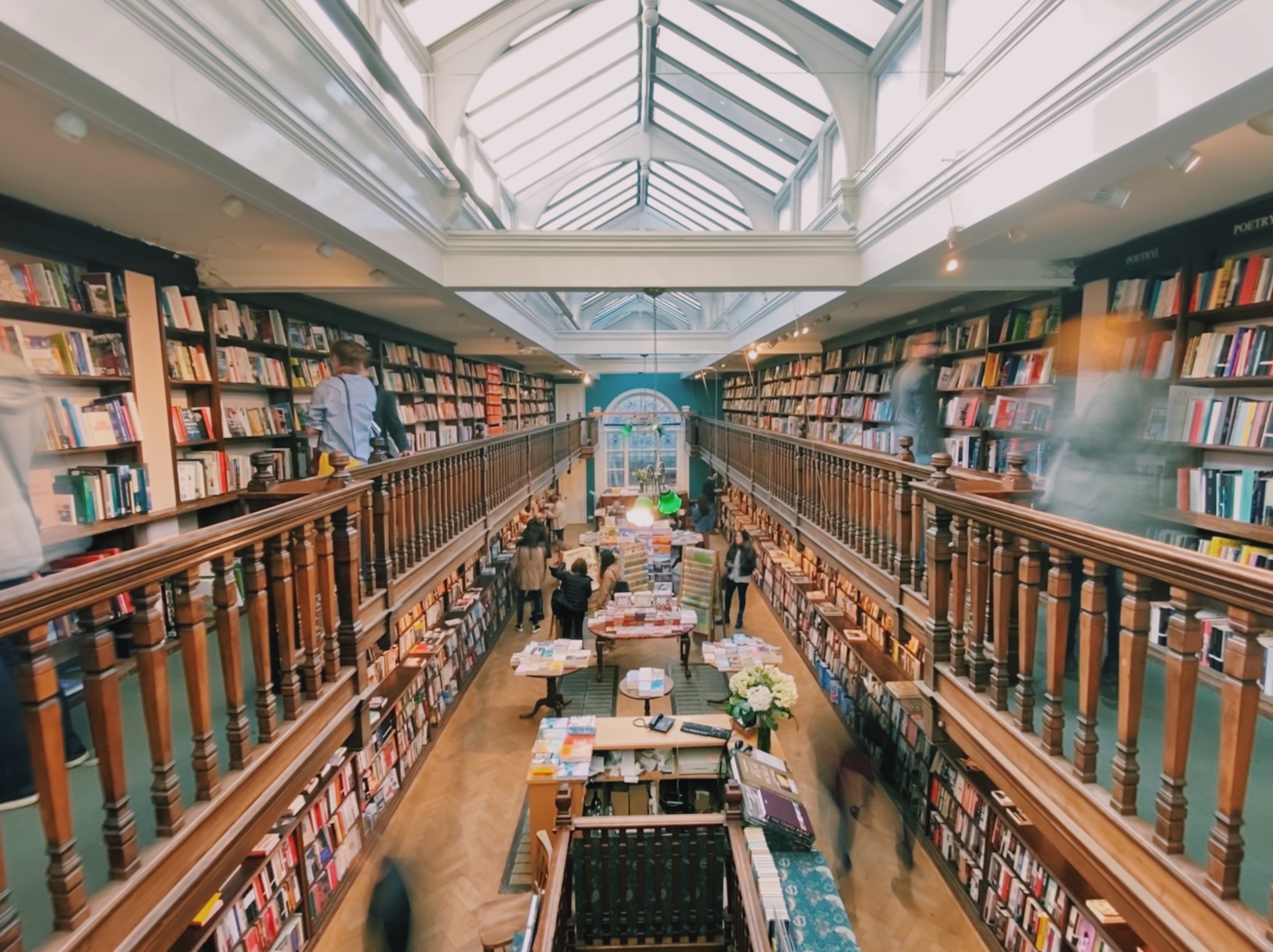 Multilevel bookstore interior with people browsing books under a skylight.