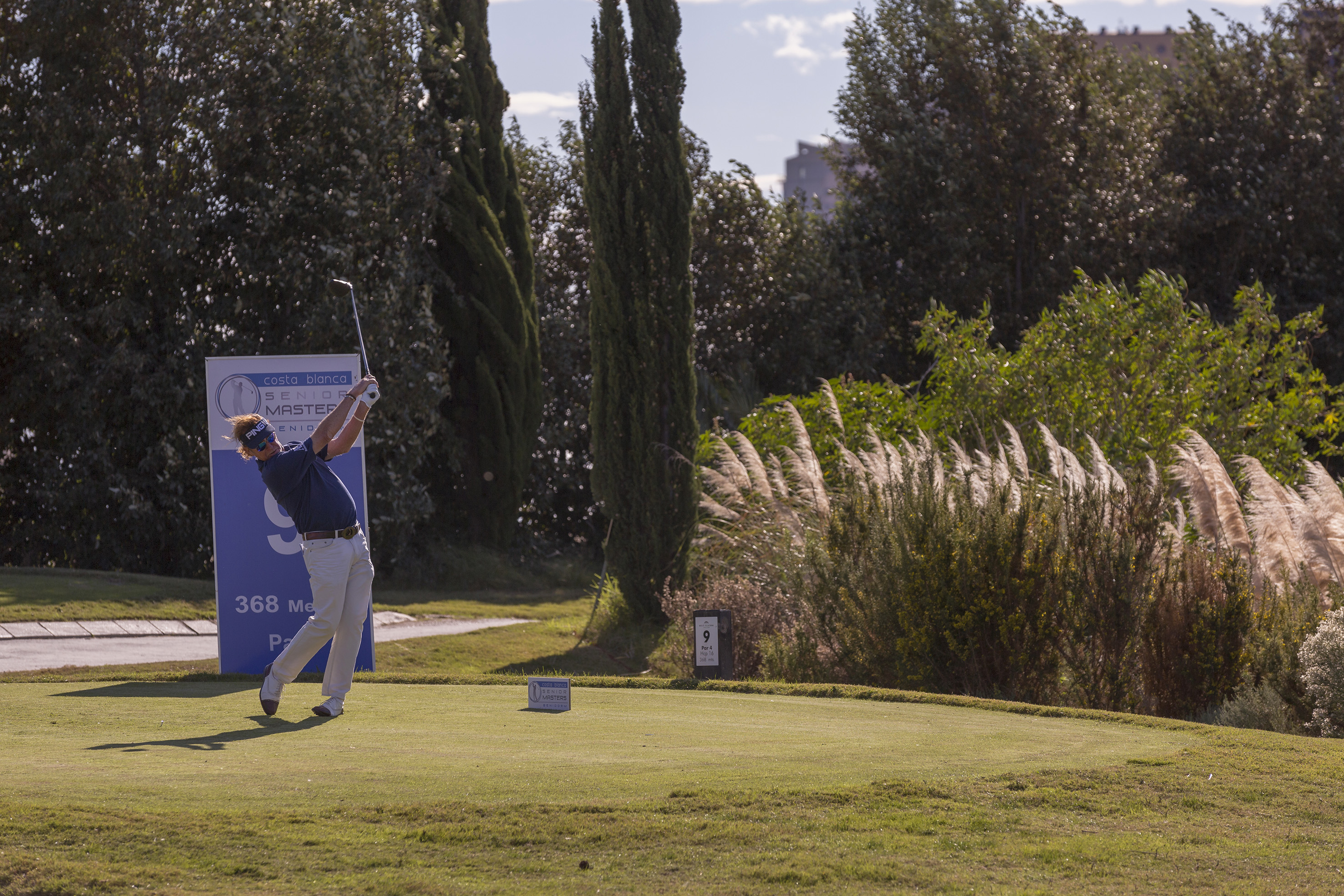 Golfer mid-swing on golf course tee. Costa Blanca Senior Master event.