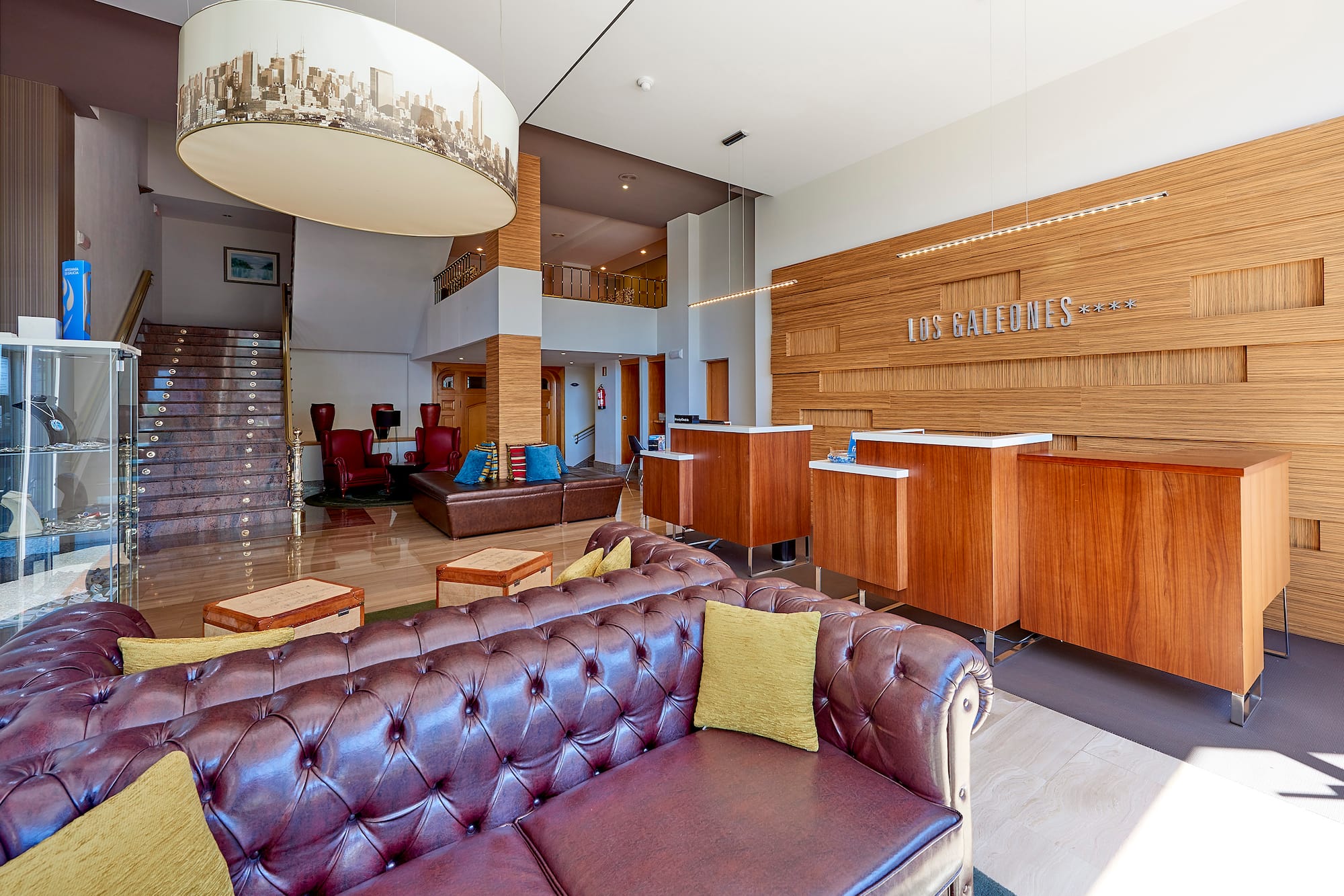 Hotel Los Galeones lobby featuring wooden reception, leather sofas, grand staircase.
