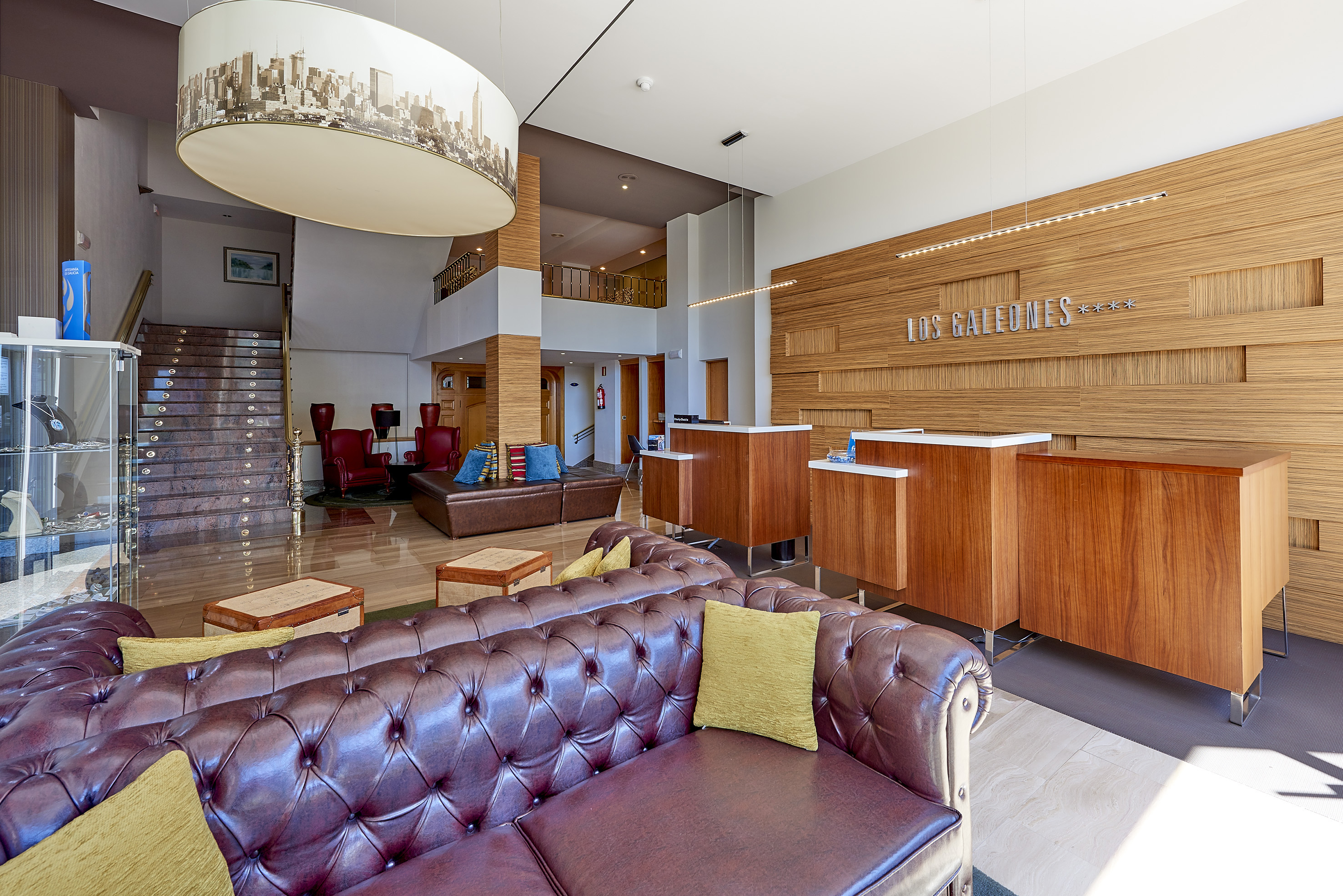 Hotel Los Galeones lobby featuring wooden reception, leather sofas, grand staircase.