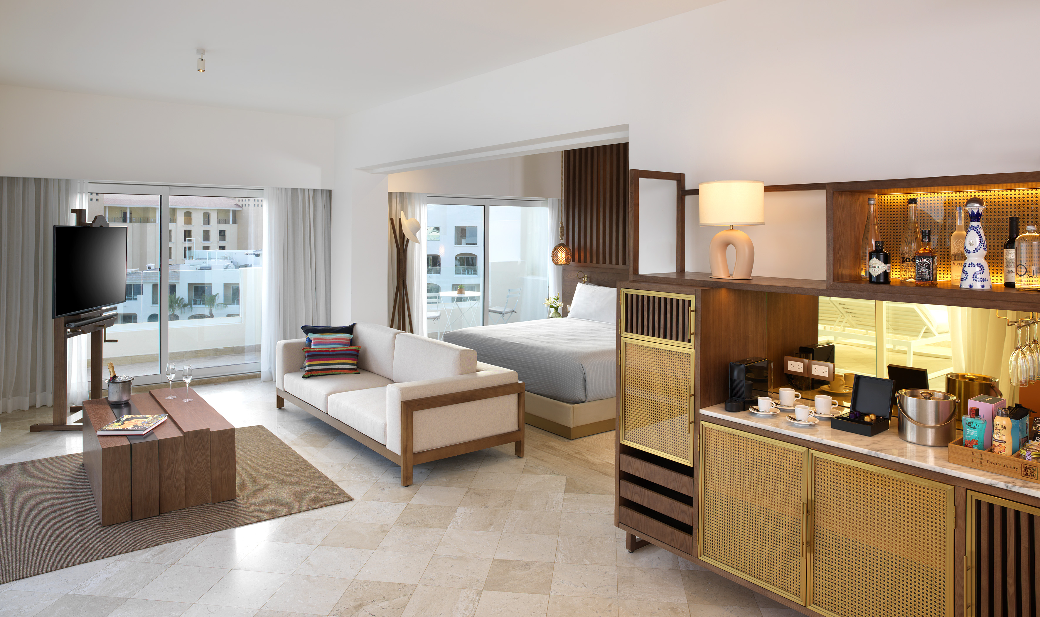 Luxury resort suite with open-plan living, bedroom, minibar, balcony.