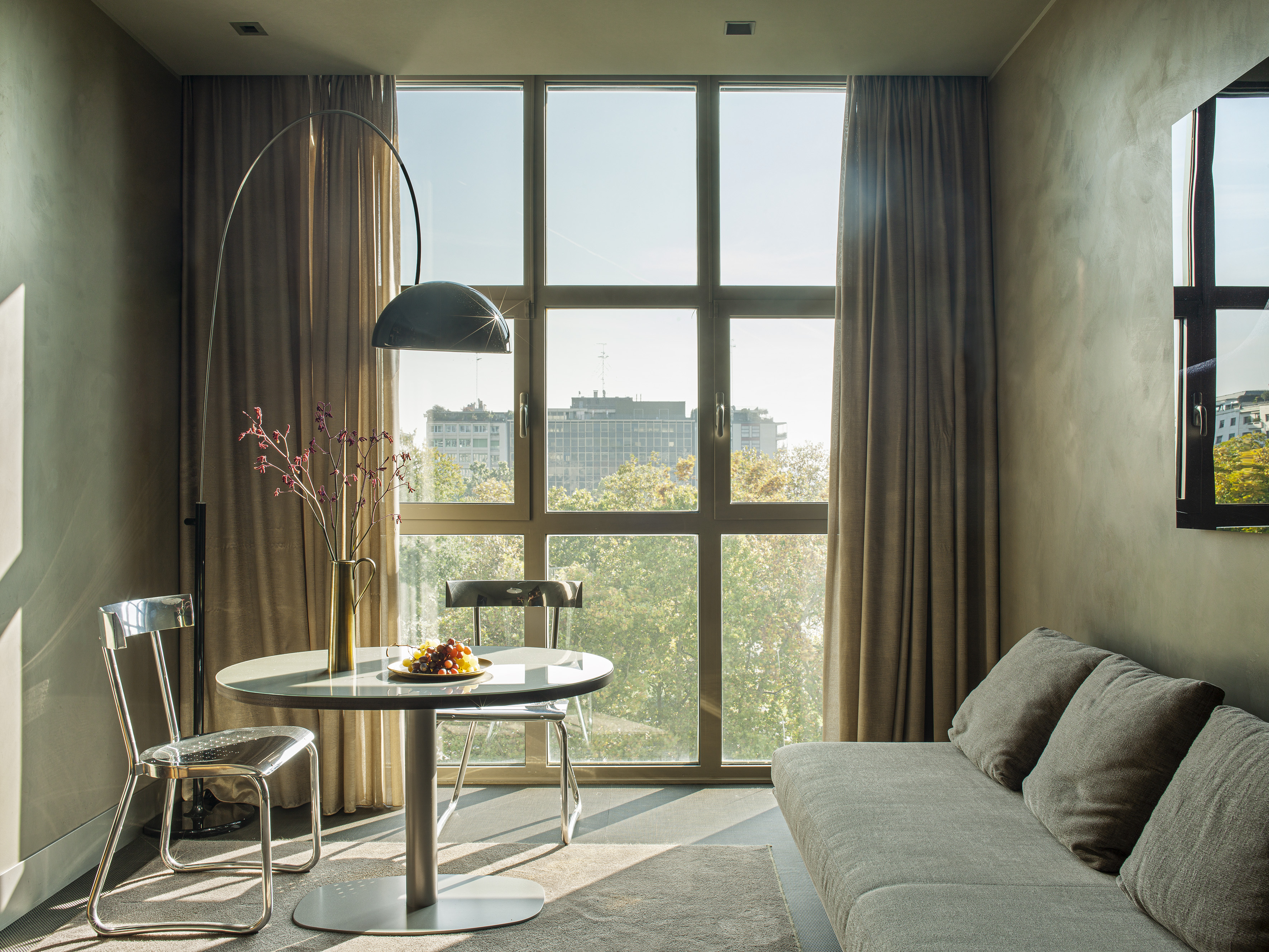 Modern living room, city view from large window, sofa, dining area, arc lamp.