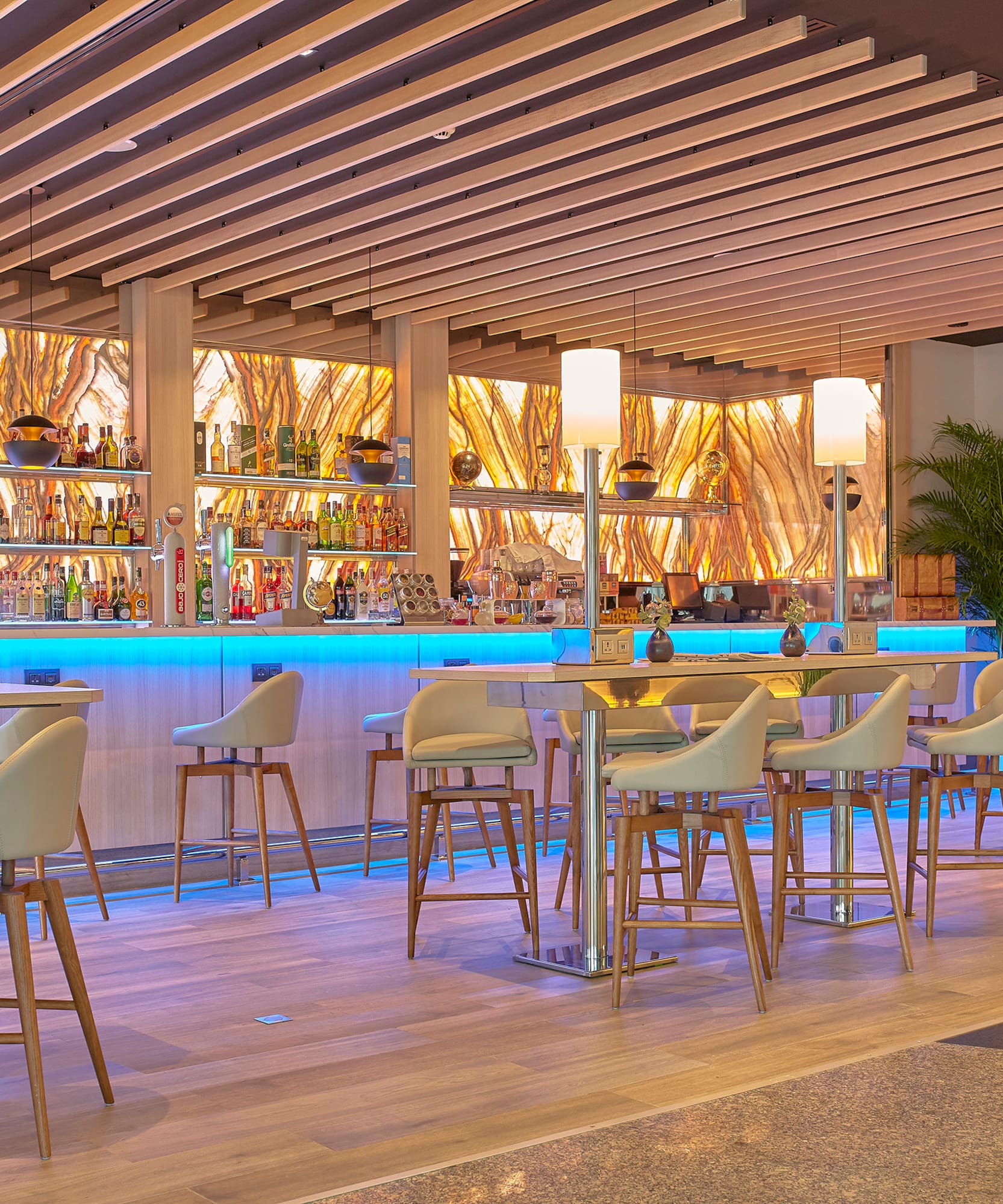 a bar with a row of chairs and a shelf with bottles
