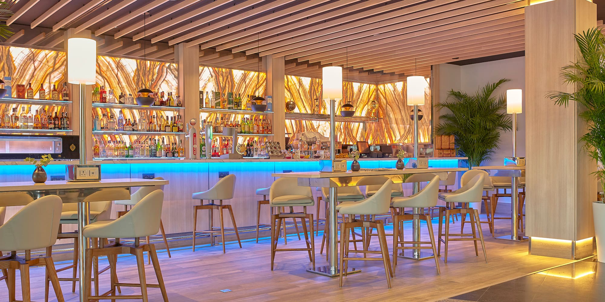 a bar with a row of chairs and a shelf with bottles