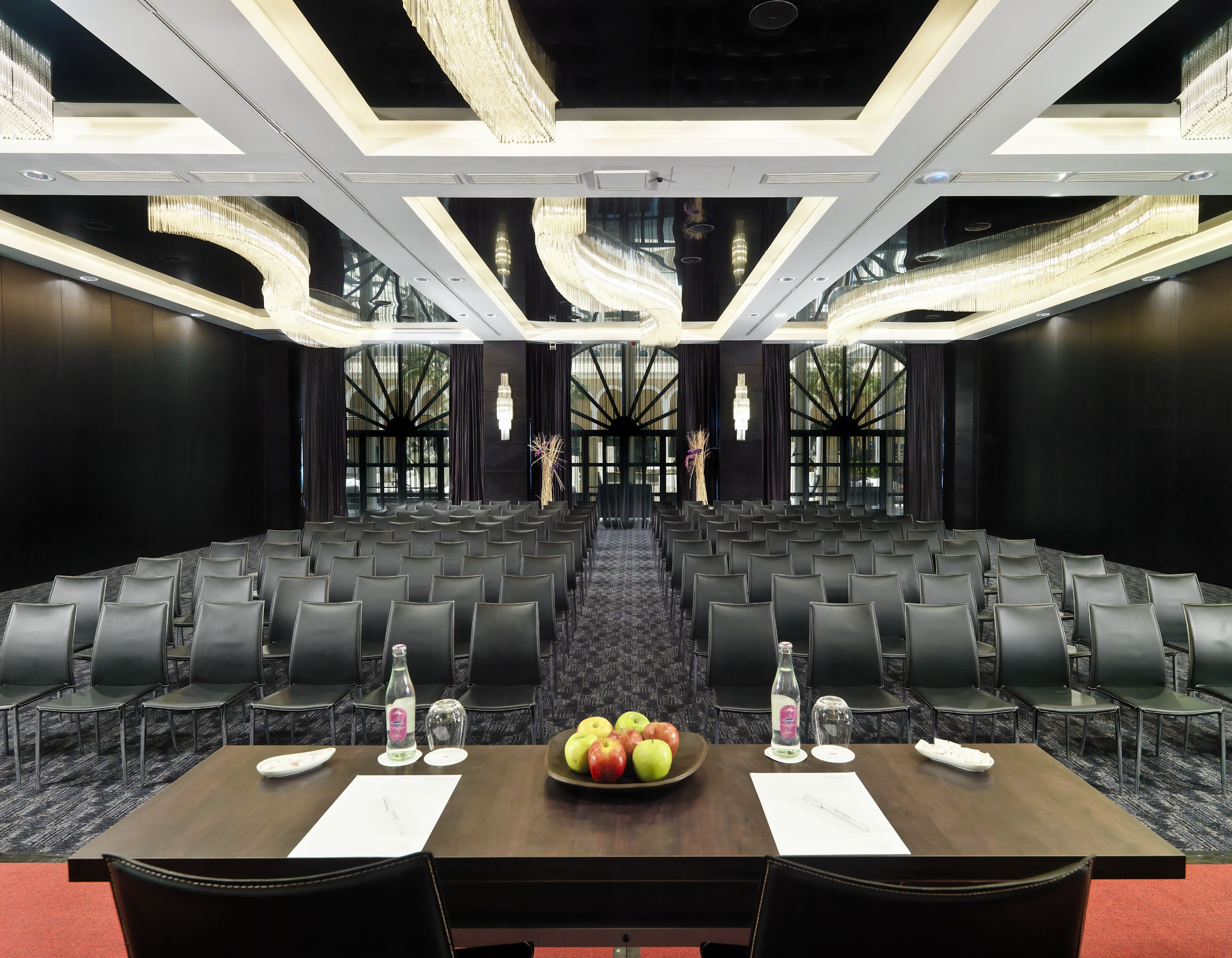 Modern conference room with black chairs, crystal chandeliers, and large windows.