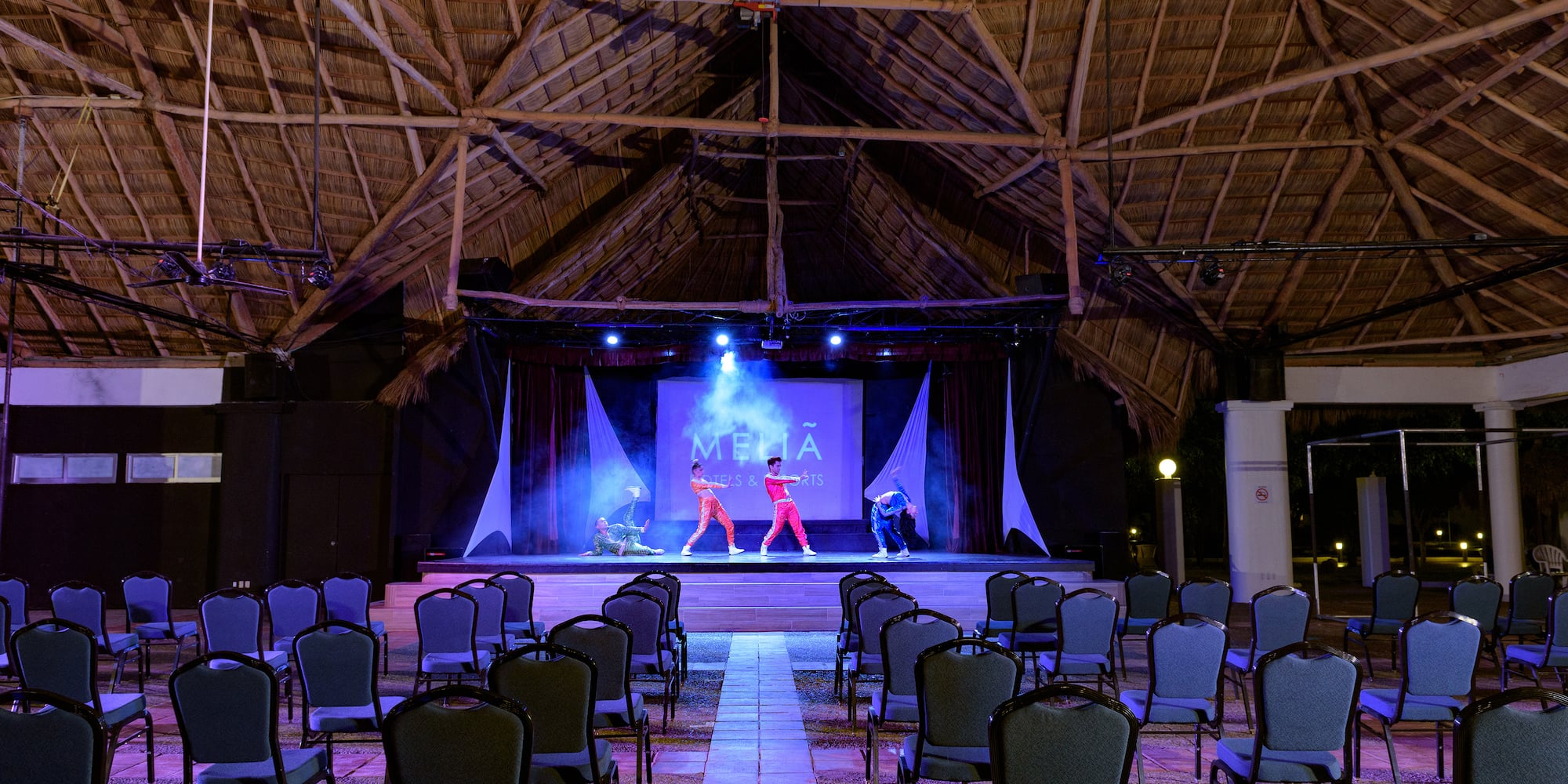 a group of people on a stage in a room with chairs