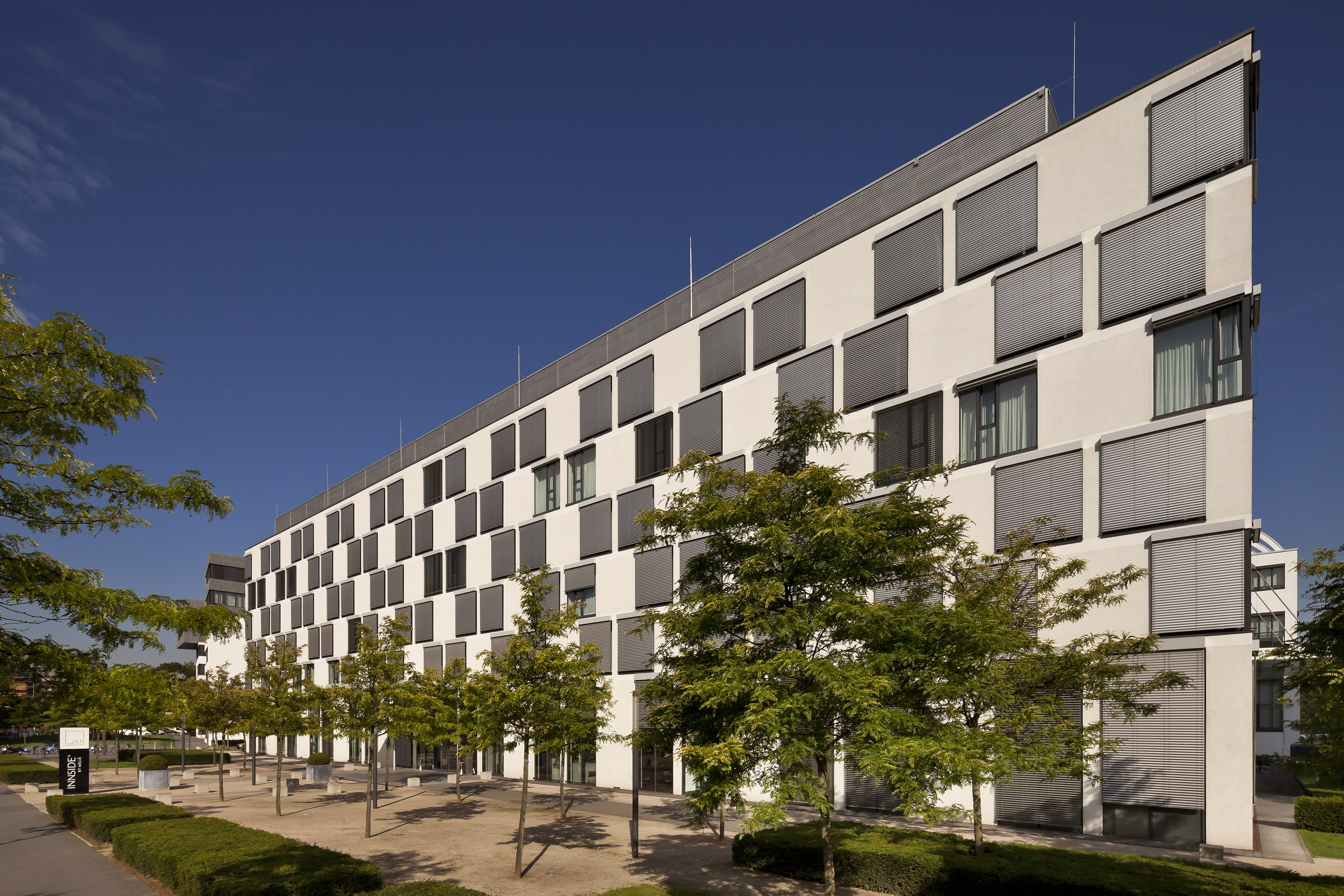 Innside by Meliá hotel exterior: modern white building, many windows, green trees.