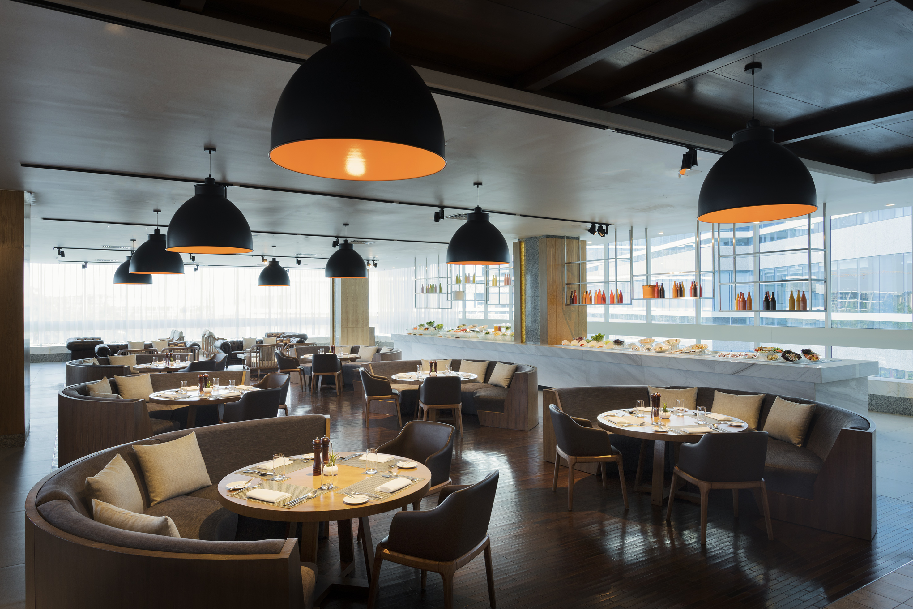 Modern restaurant buffet with booth seating, pendant lights, and dark wood floor.