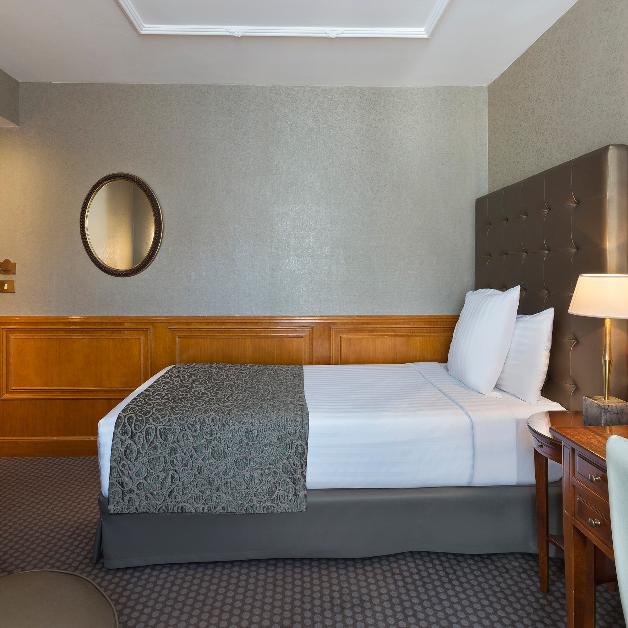 a bed with a lamp and a mirror